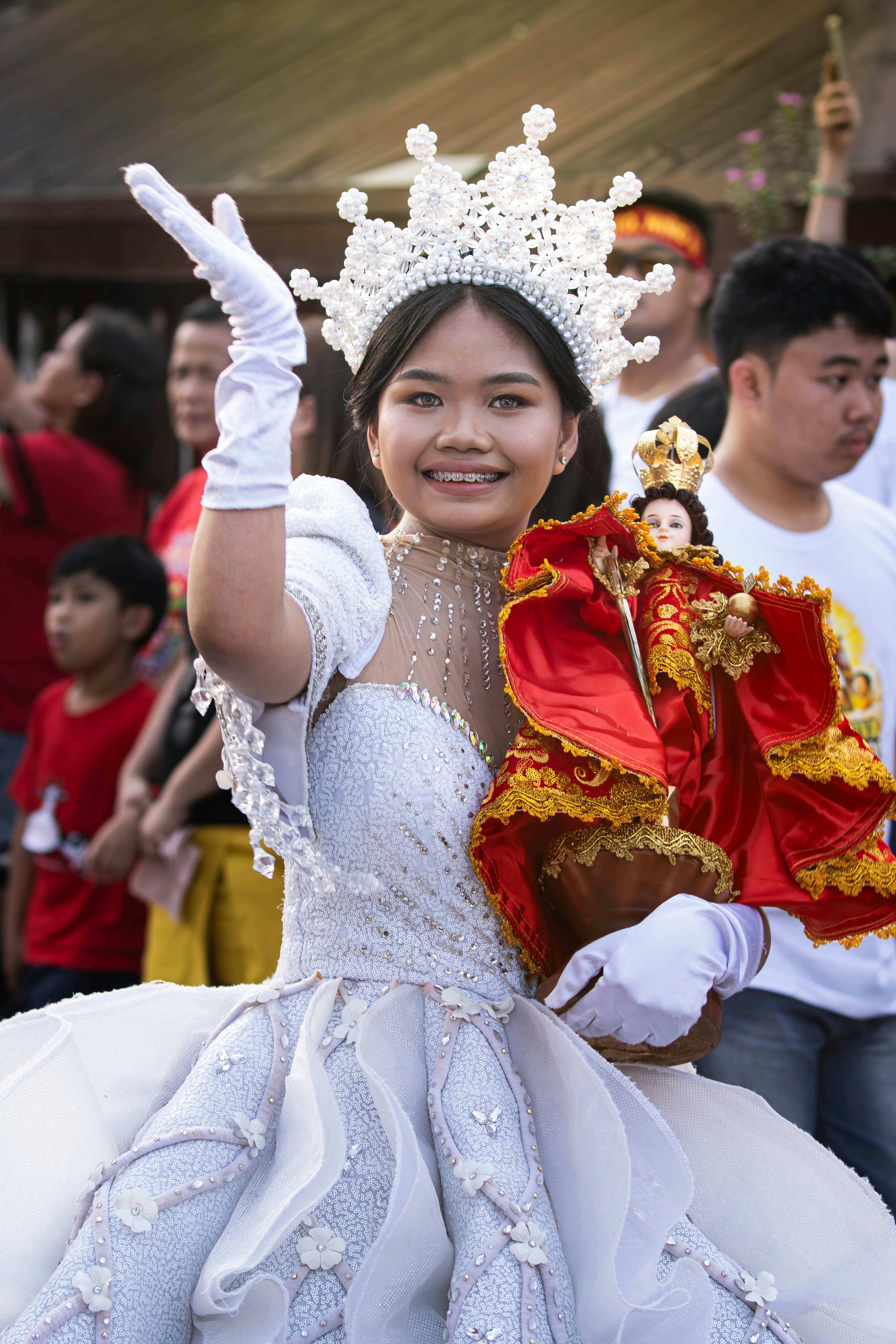 Junge Frau in prunkvoller Kleidung, die religiöse Statue hält