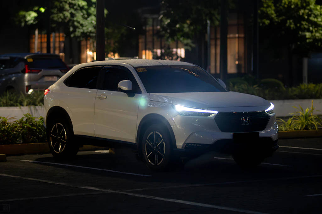 A white honda suv parked at night with headlights on