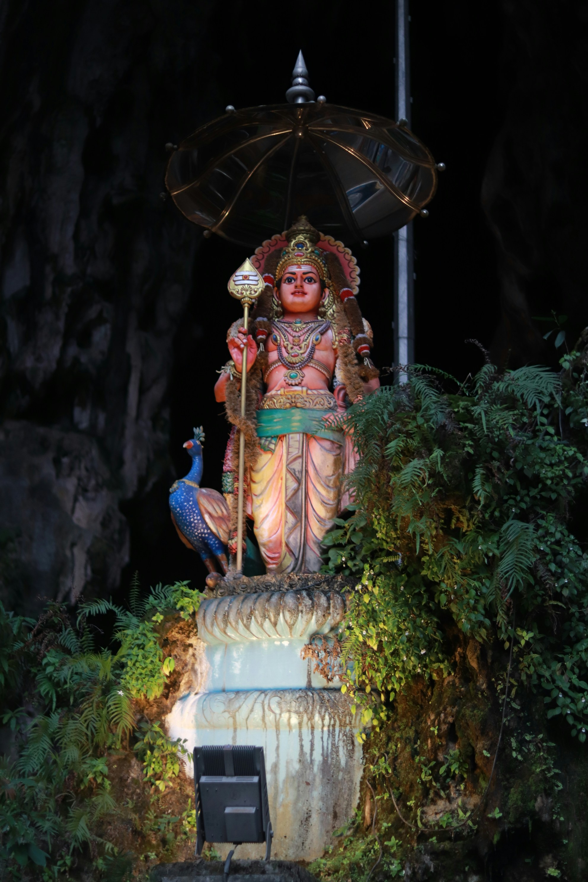 Une statue colorée d’une divinité avec un paon