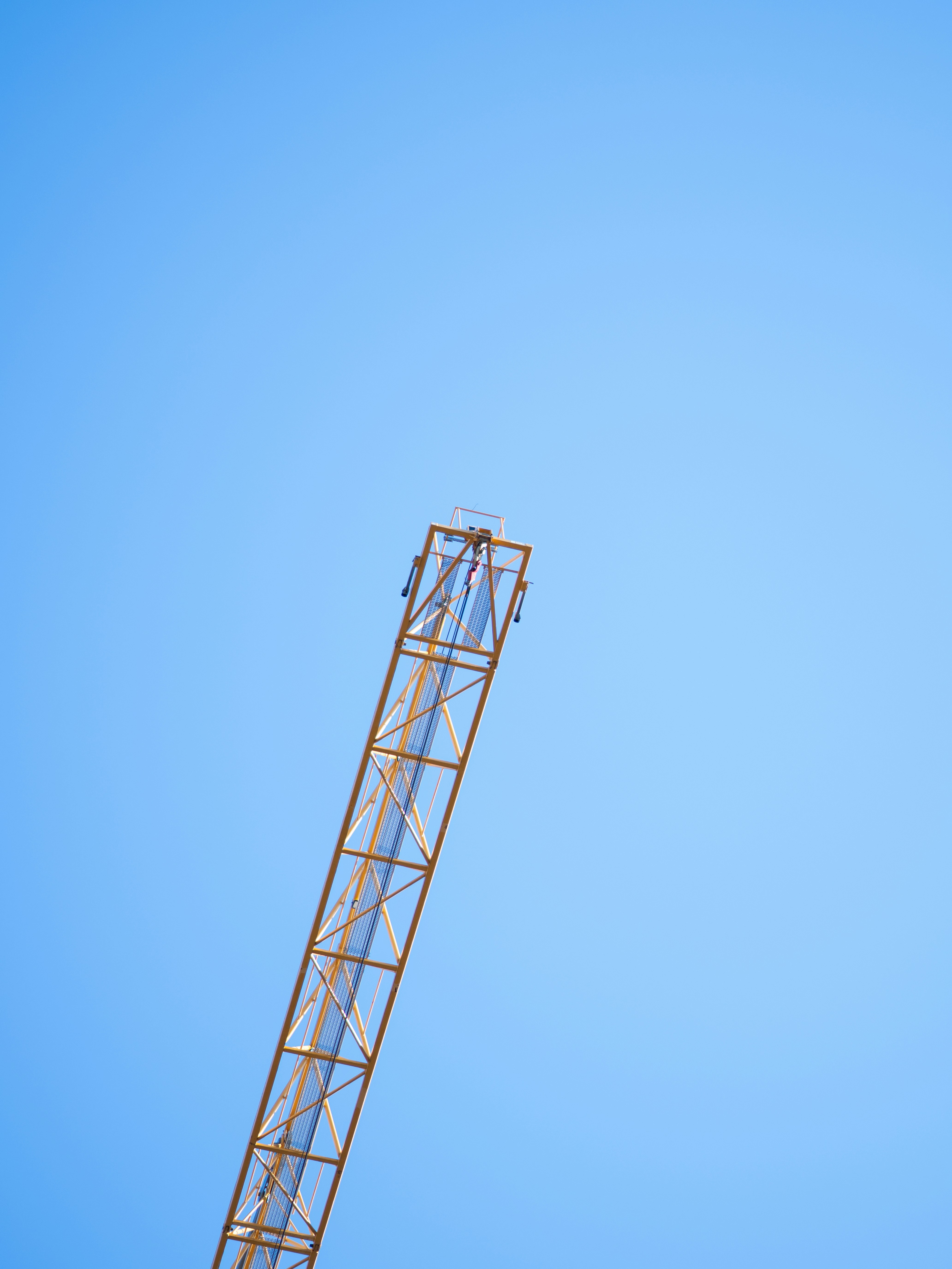 A yellow crane against a clear blue sky