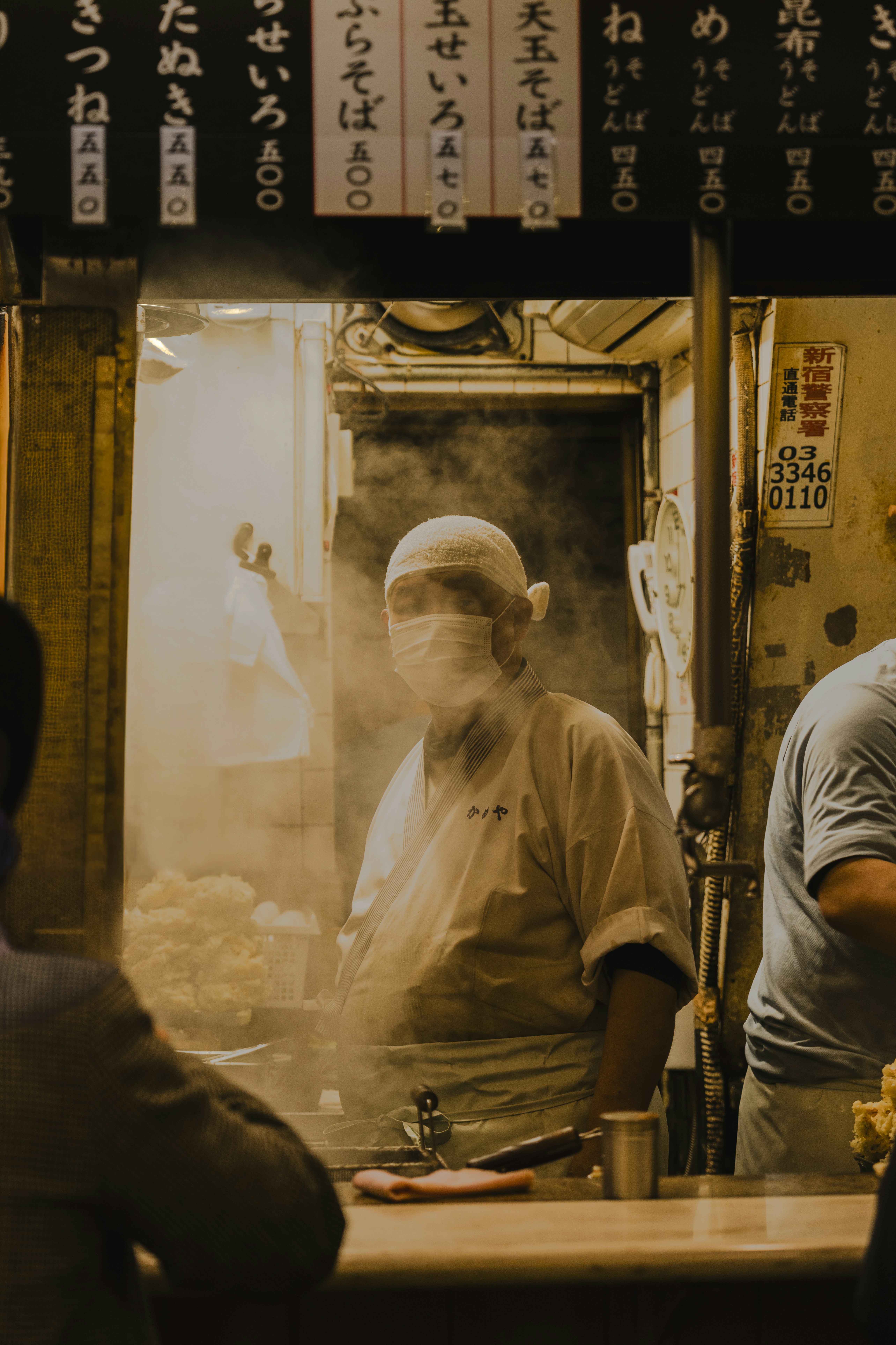 Chef in mask cooking in steamy restaurant kitchen