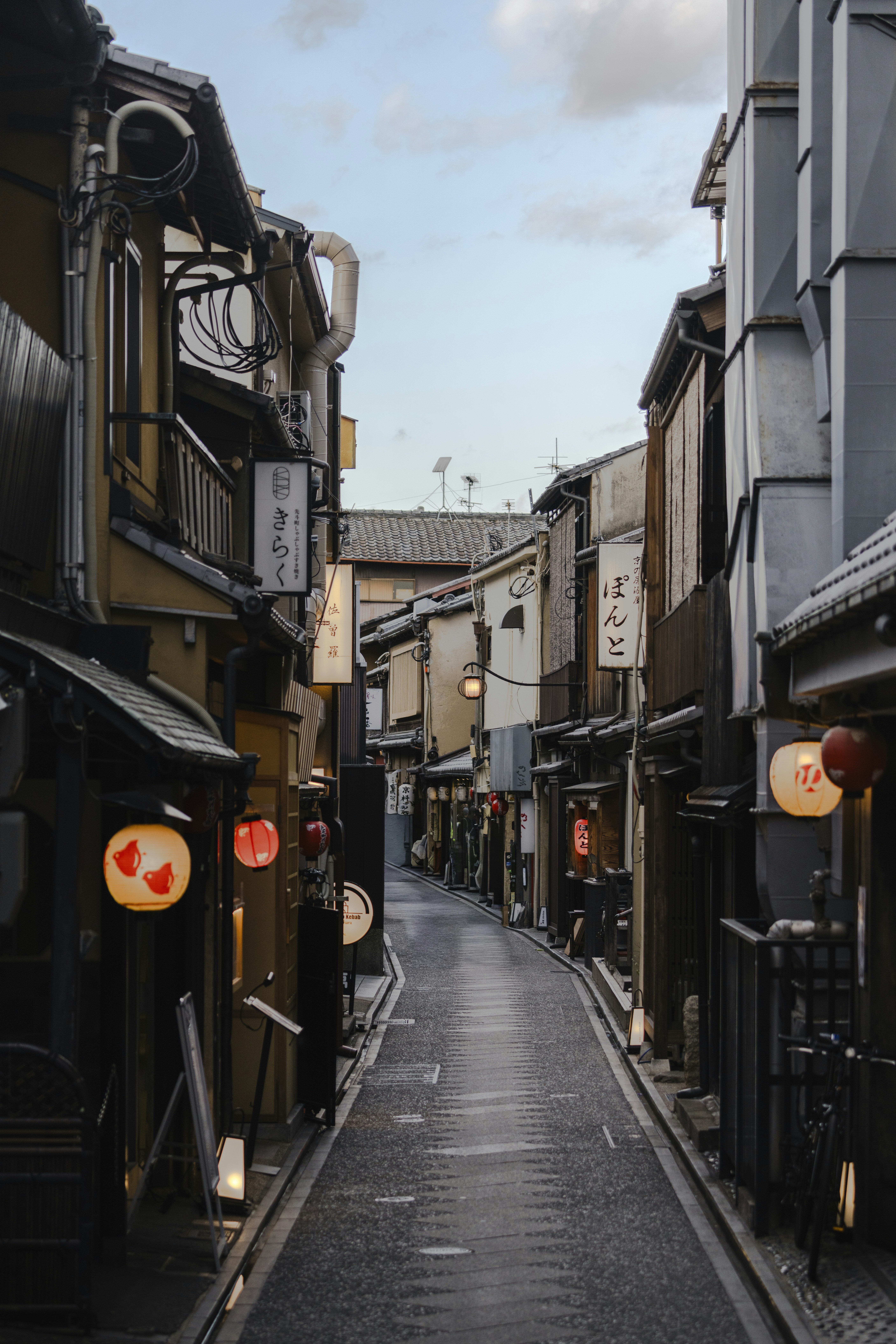 Narrow street with traditional japanese buildings and lanterns.