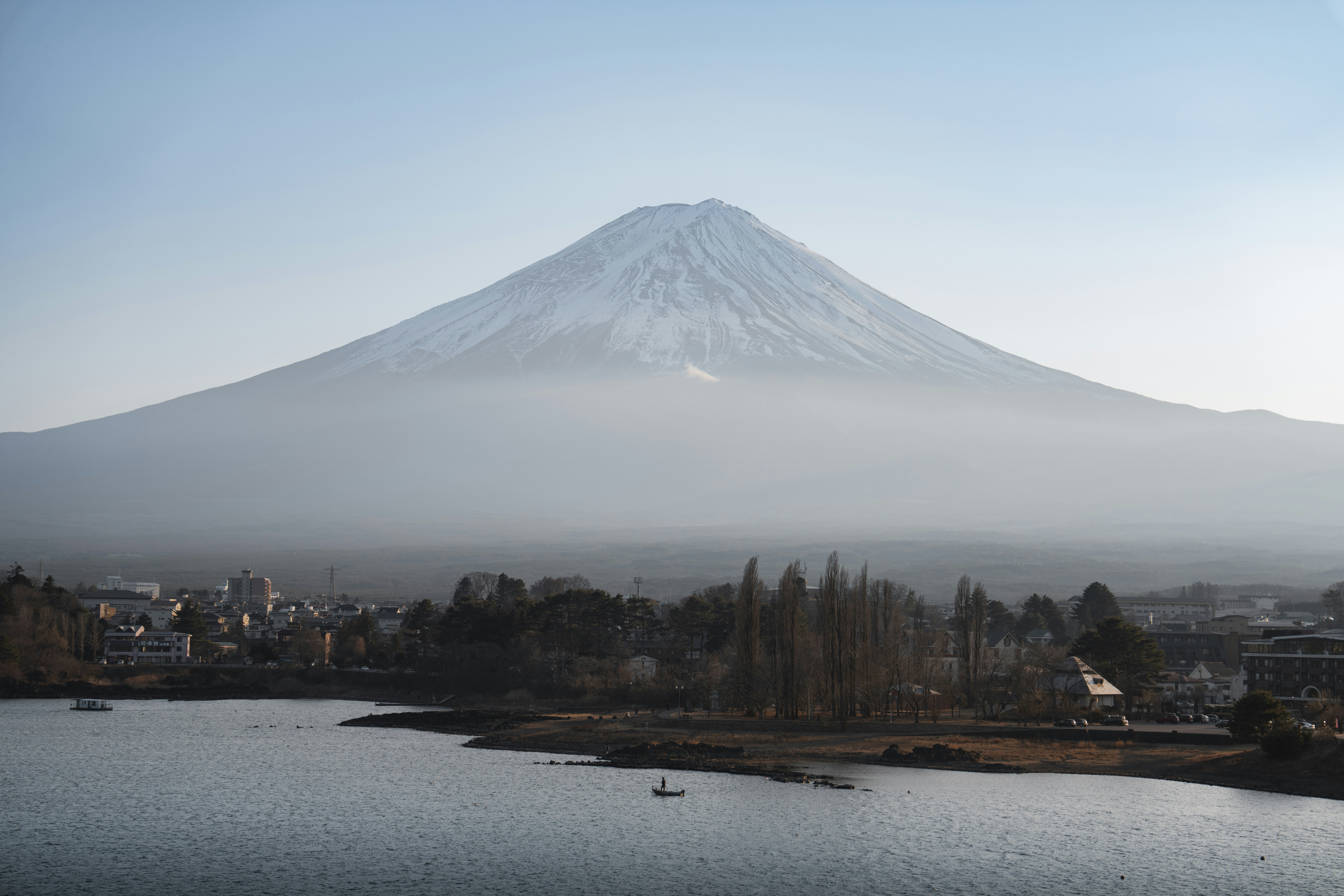 Snow-capped mount fuji looms over a misty japanese town.