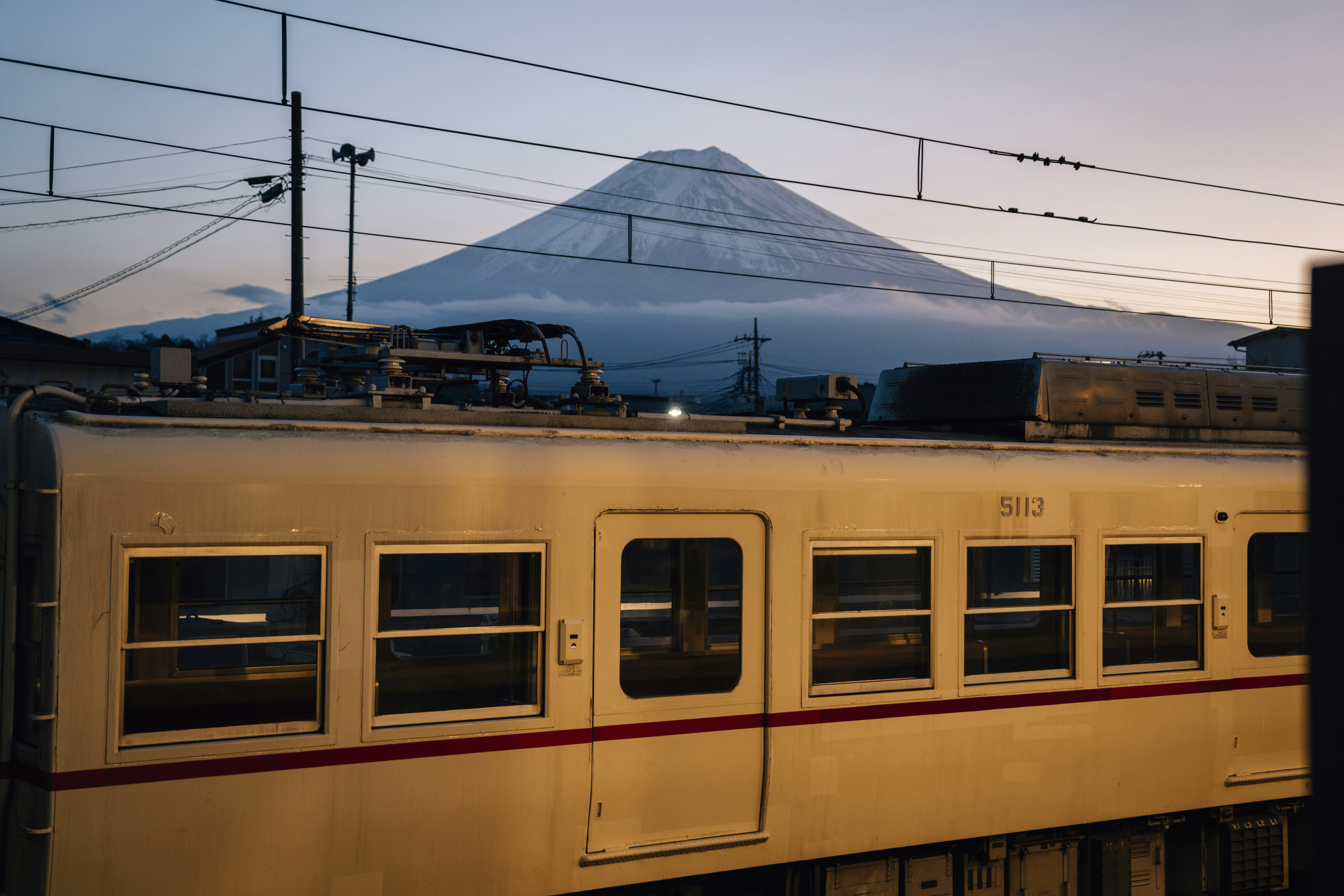 Train passes mount fuji at dusk.