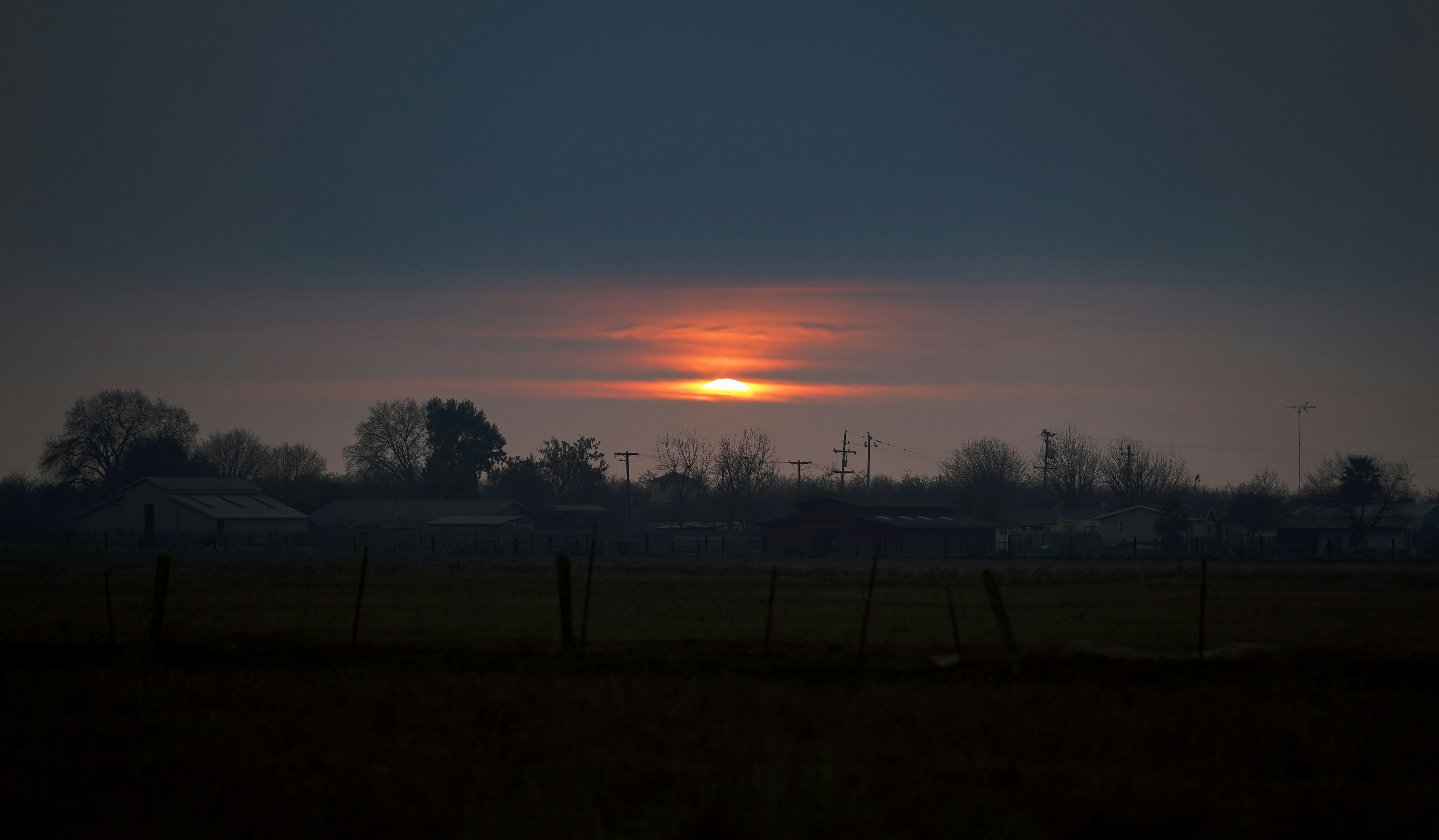 Sunrise over a dark, rural landscape