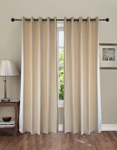 Beige curtains hang over a window with a lamp
