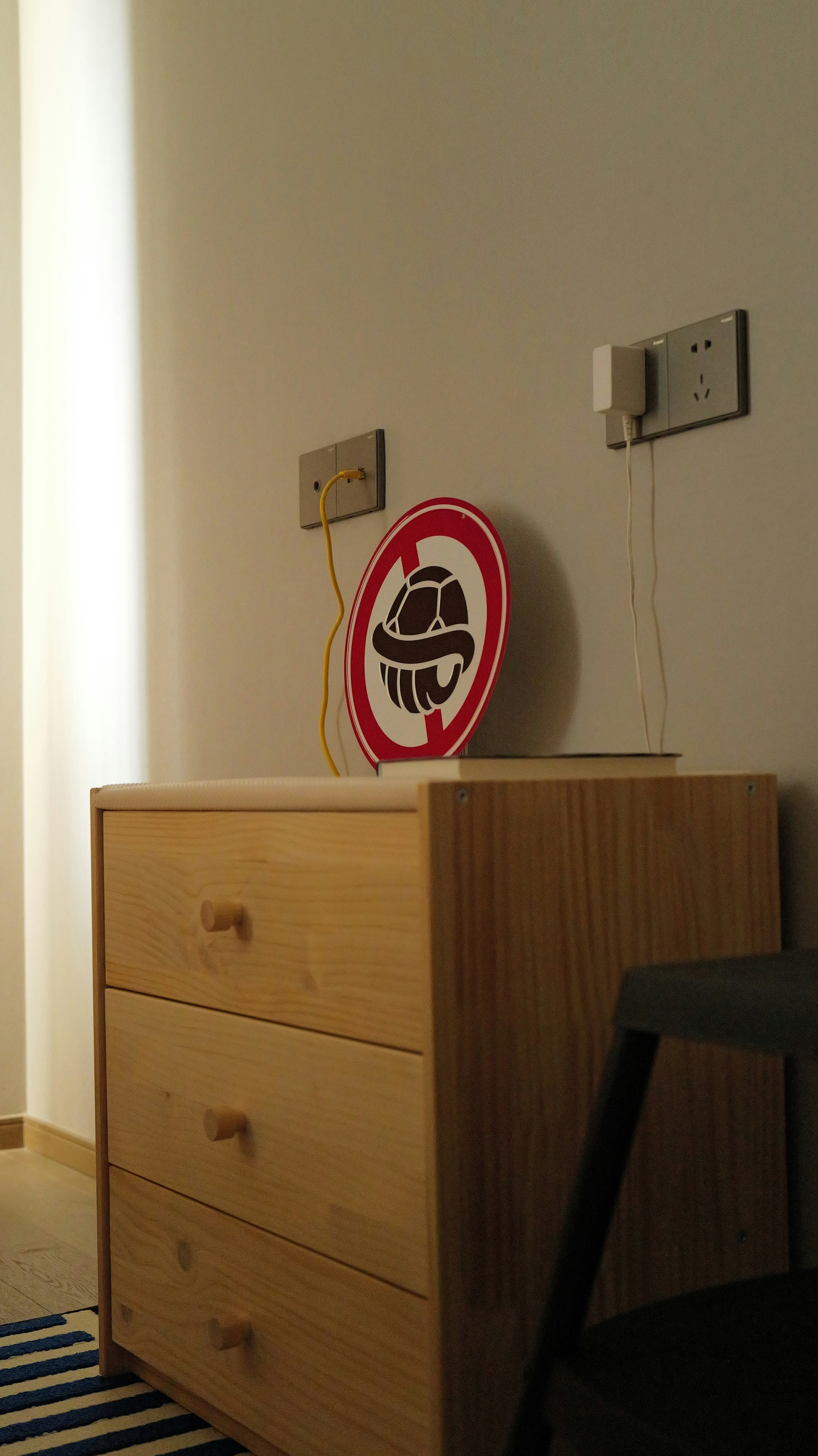 Wooden dresser with a sign and electrical outlets.