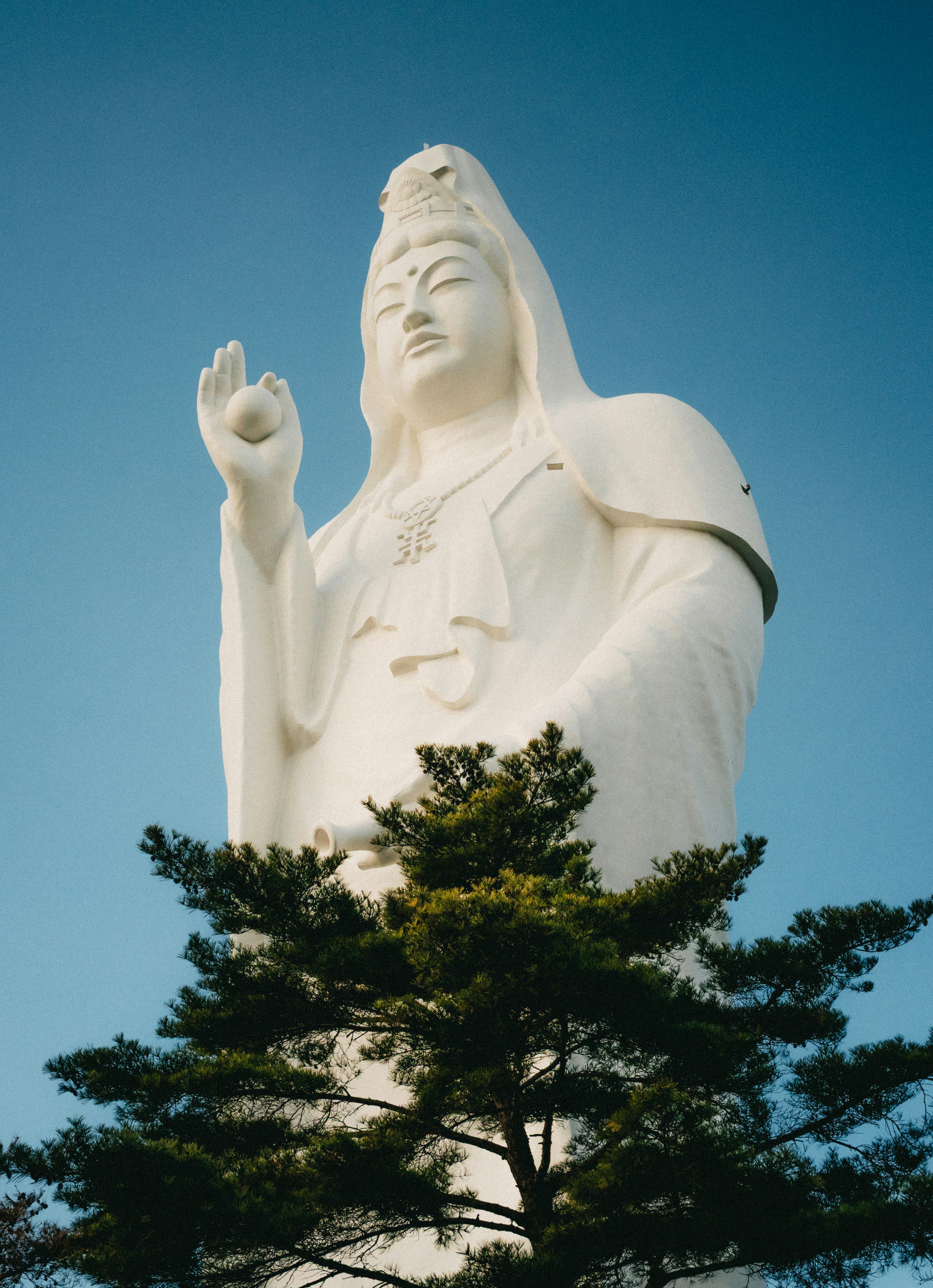 Una statua bianca alta contro un cielo azzurro limpido.