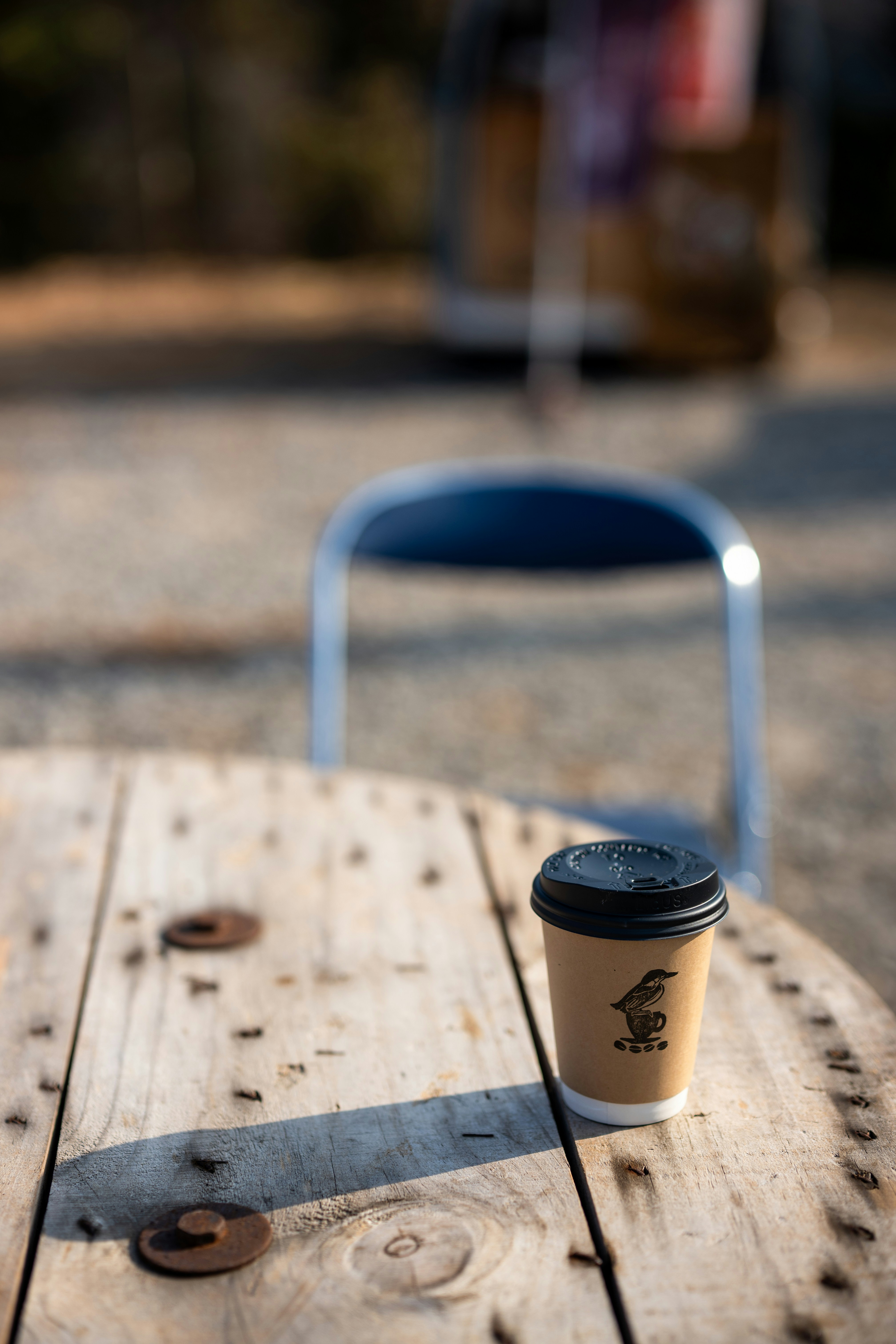 Una tazza usa e getta poggia su un tavolino a bobina di legno.