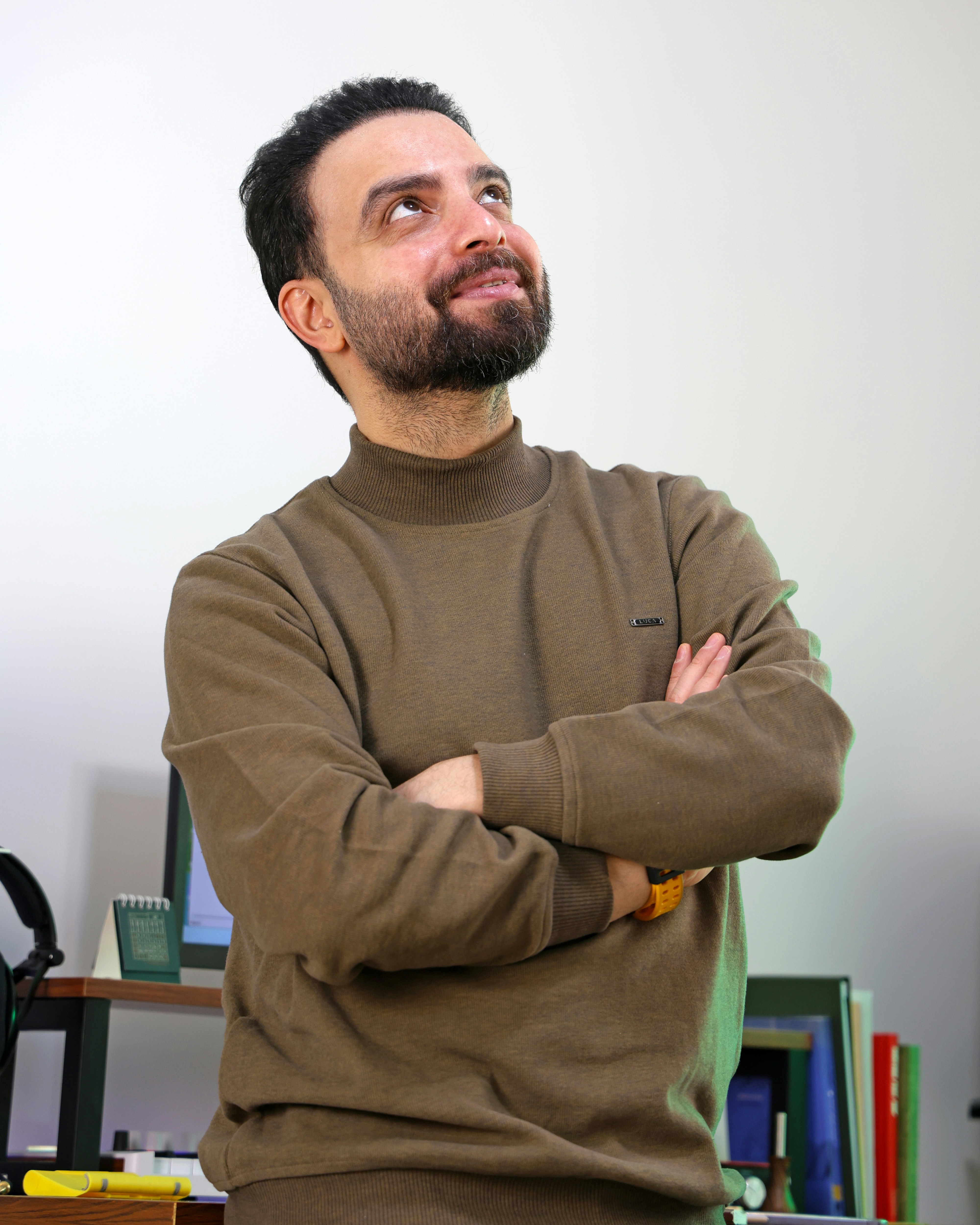 Man with beard looking up with arms crossed