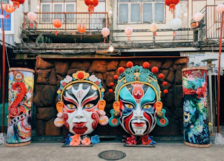 Two ornate masks with elaborate makeup and headdresses.