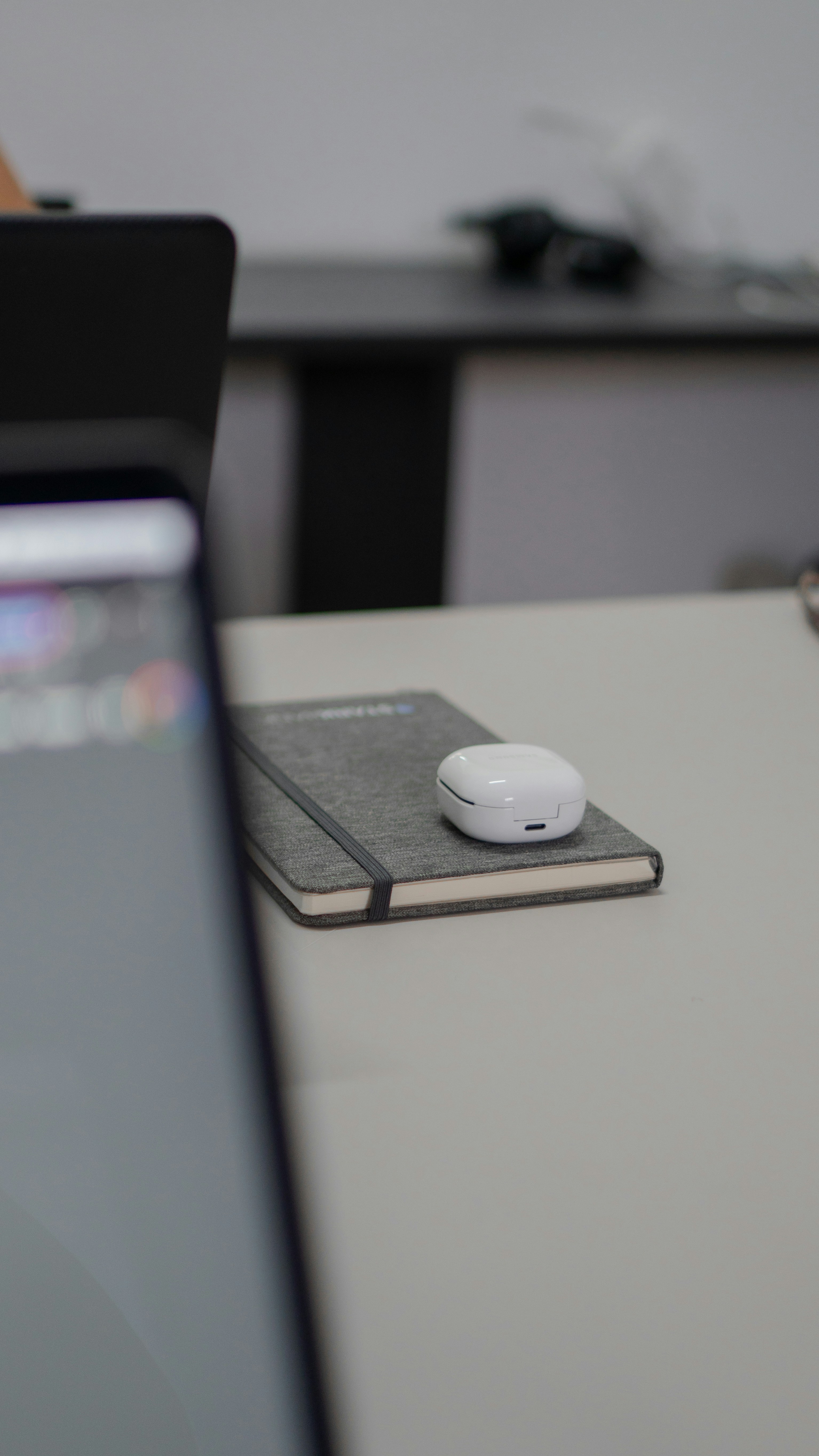 A notebook with wireless earbuds on a desk.