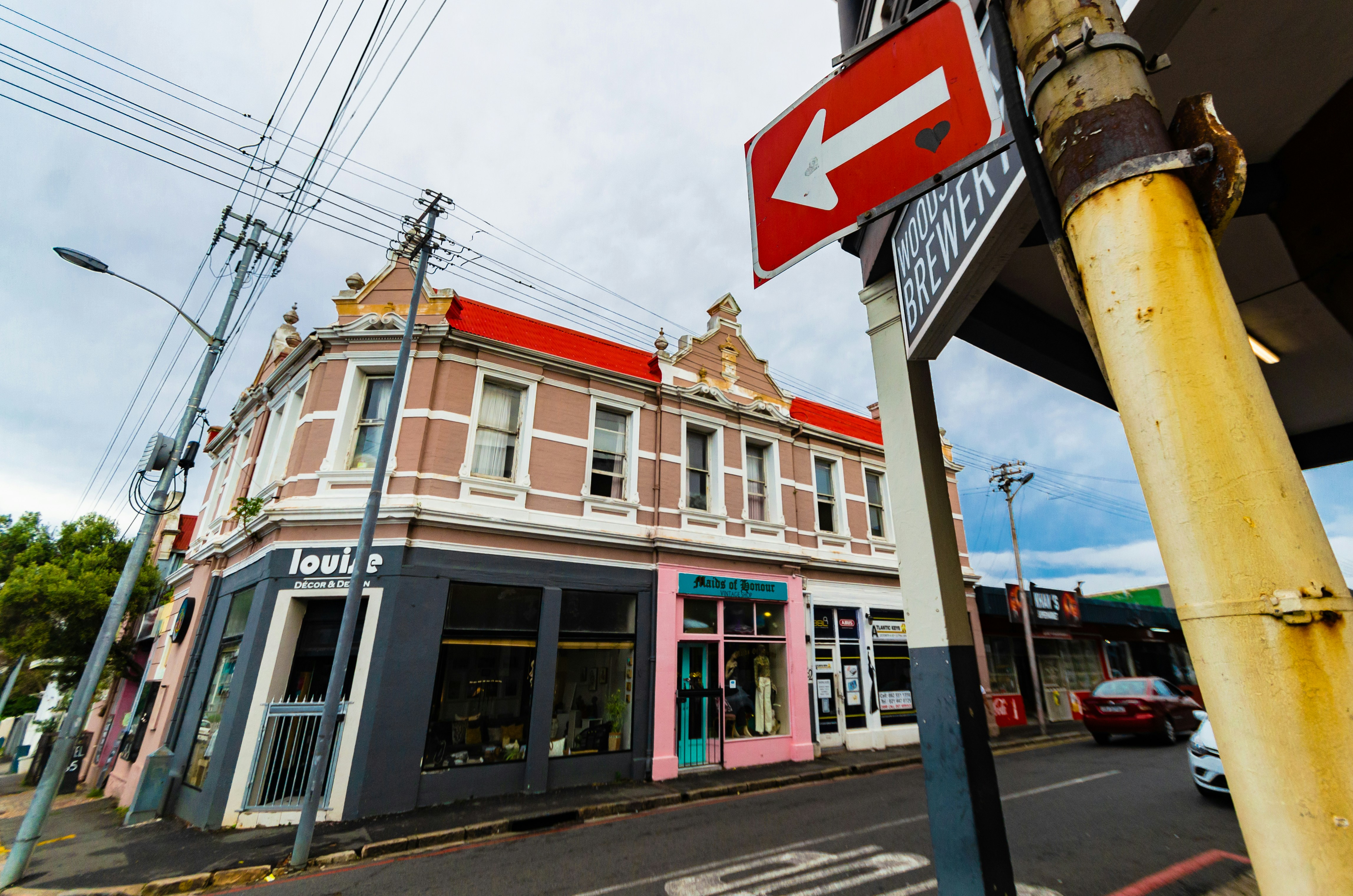 Edificio all'angolo con negozi e un cartello a freccia rossa.