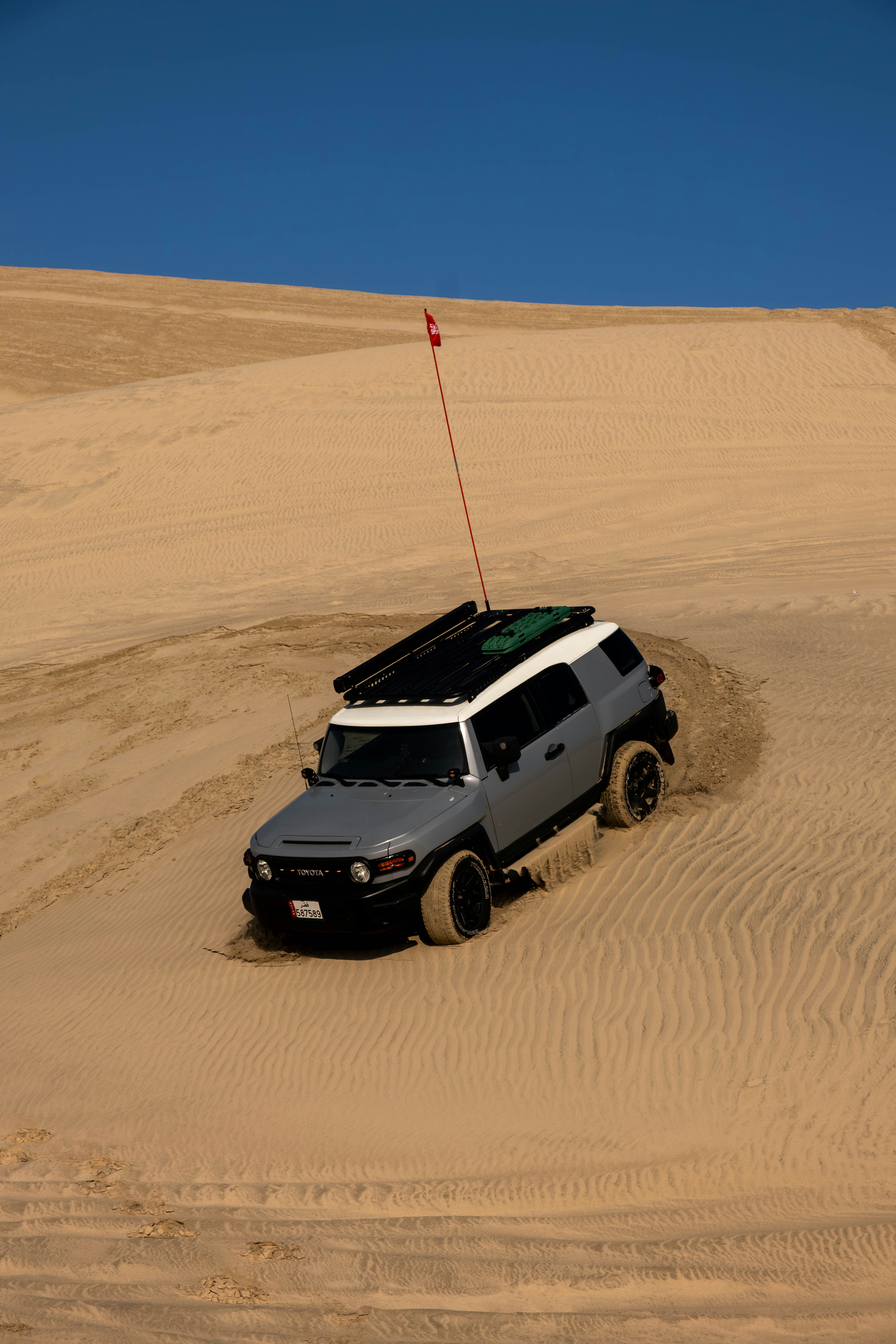 Gray suv driving up a sand dune