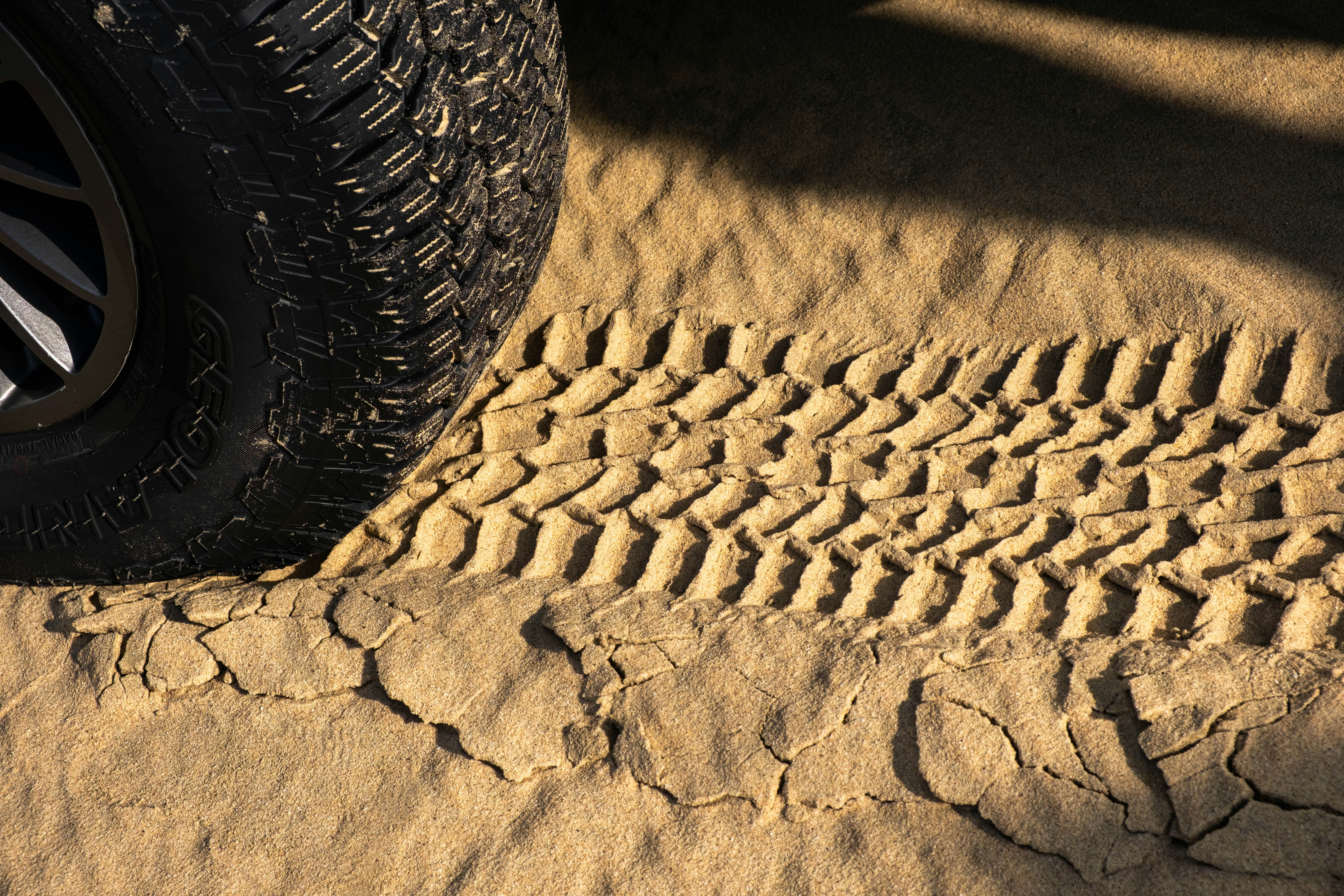 A tire track imprinted in dry desert sand