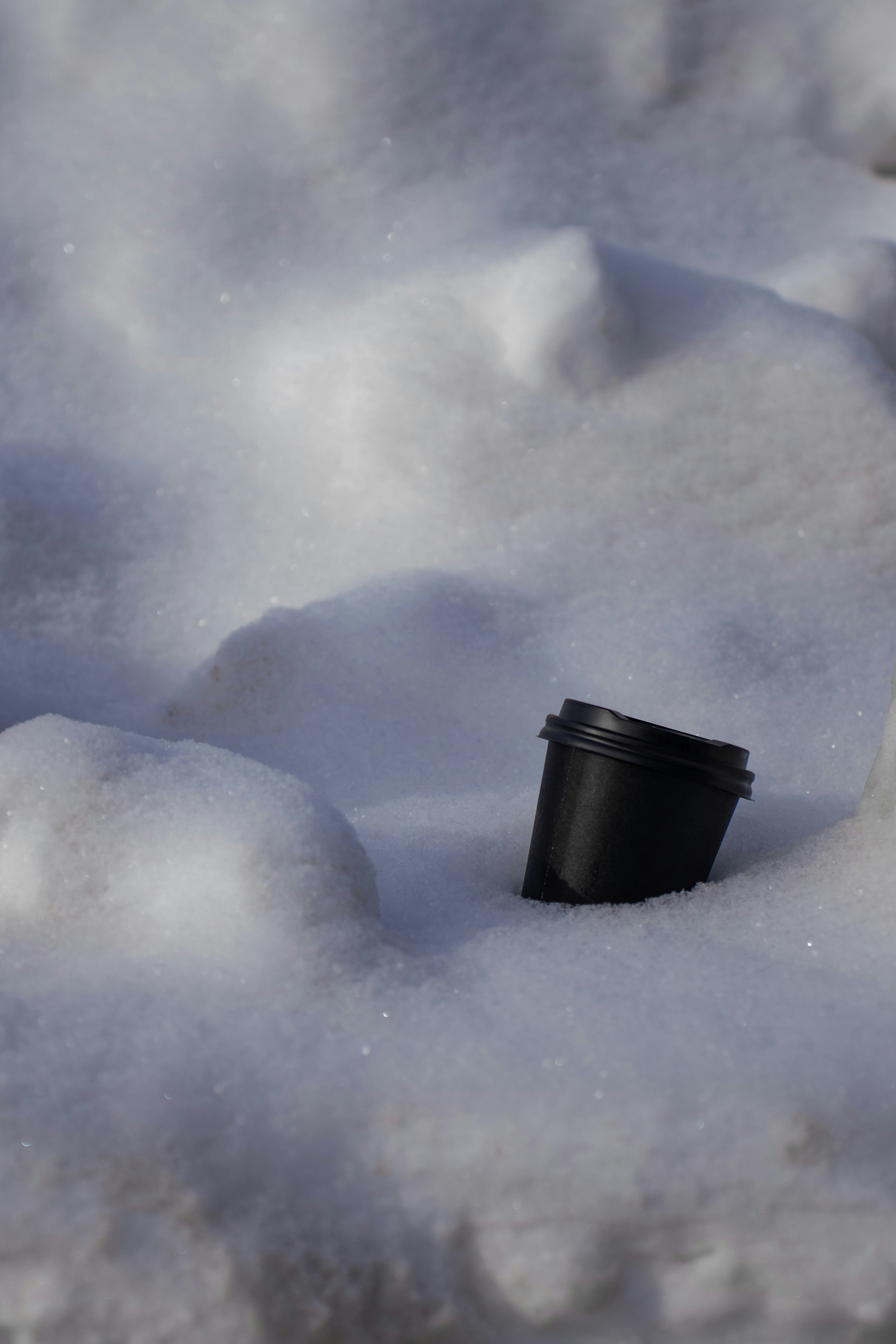 Uma taça preta repousa na neve branca.
