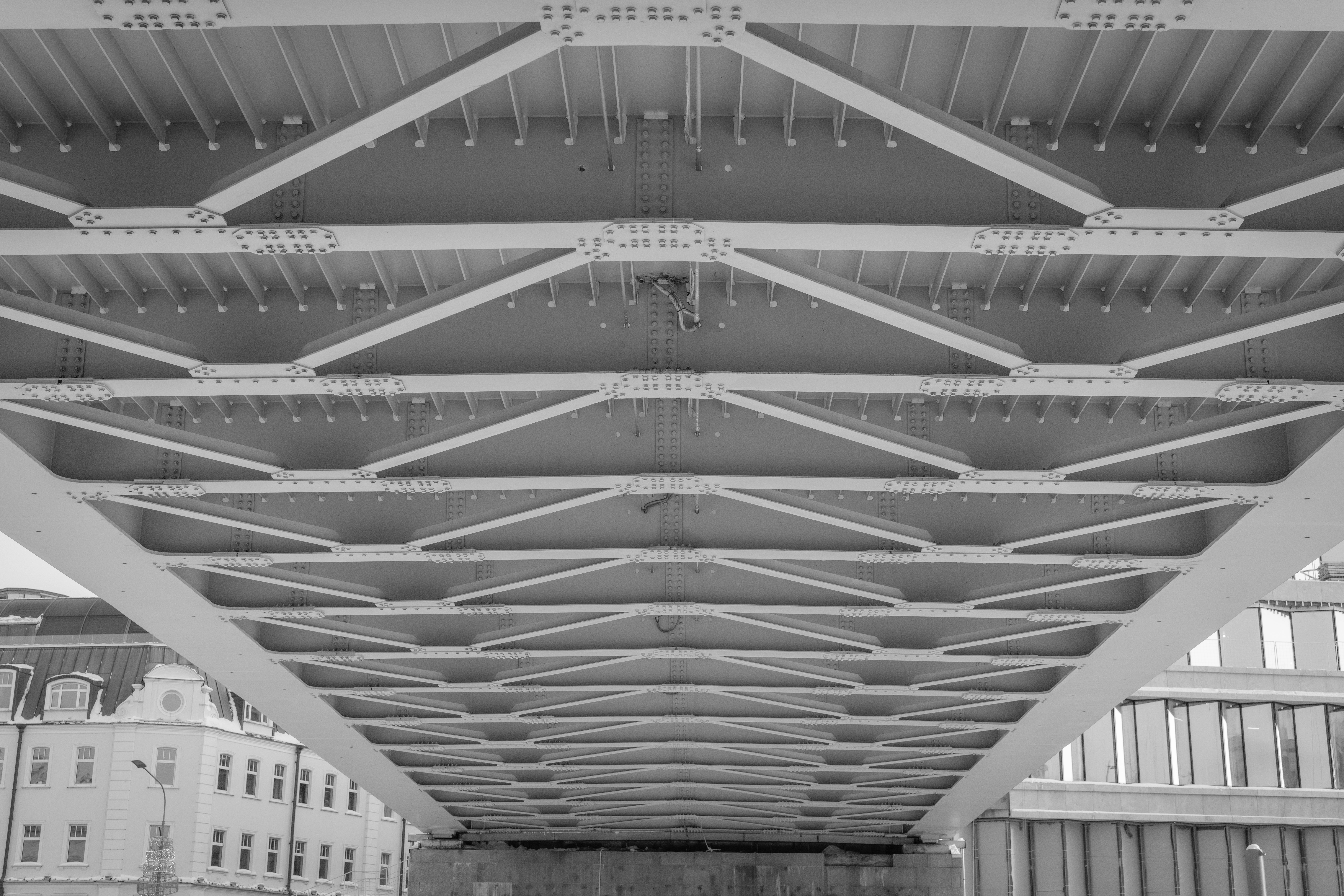 Parte inferior de uma estrutura de ponte de aço com padrões geométricos.
