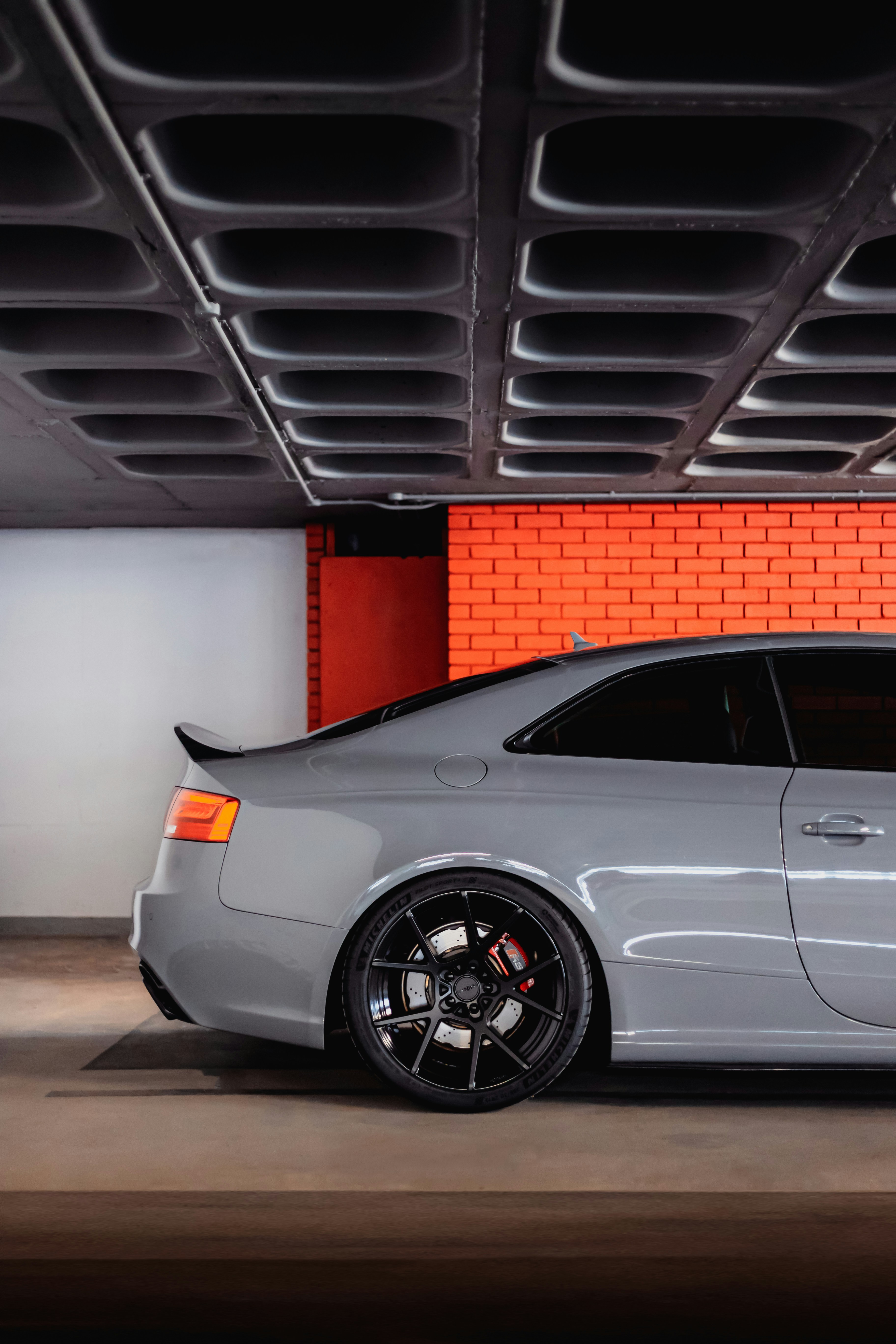Grey sports car parked in a garage with orange wall