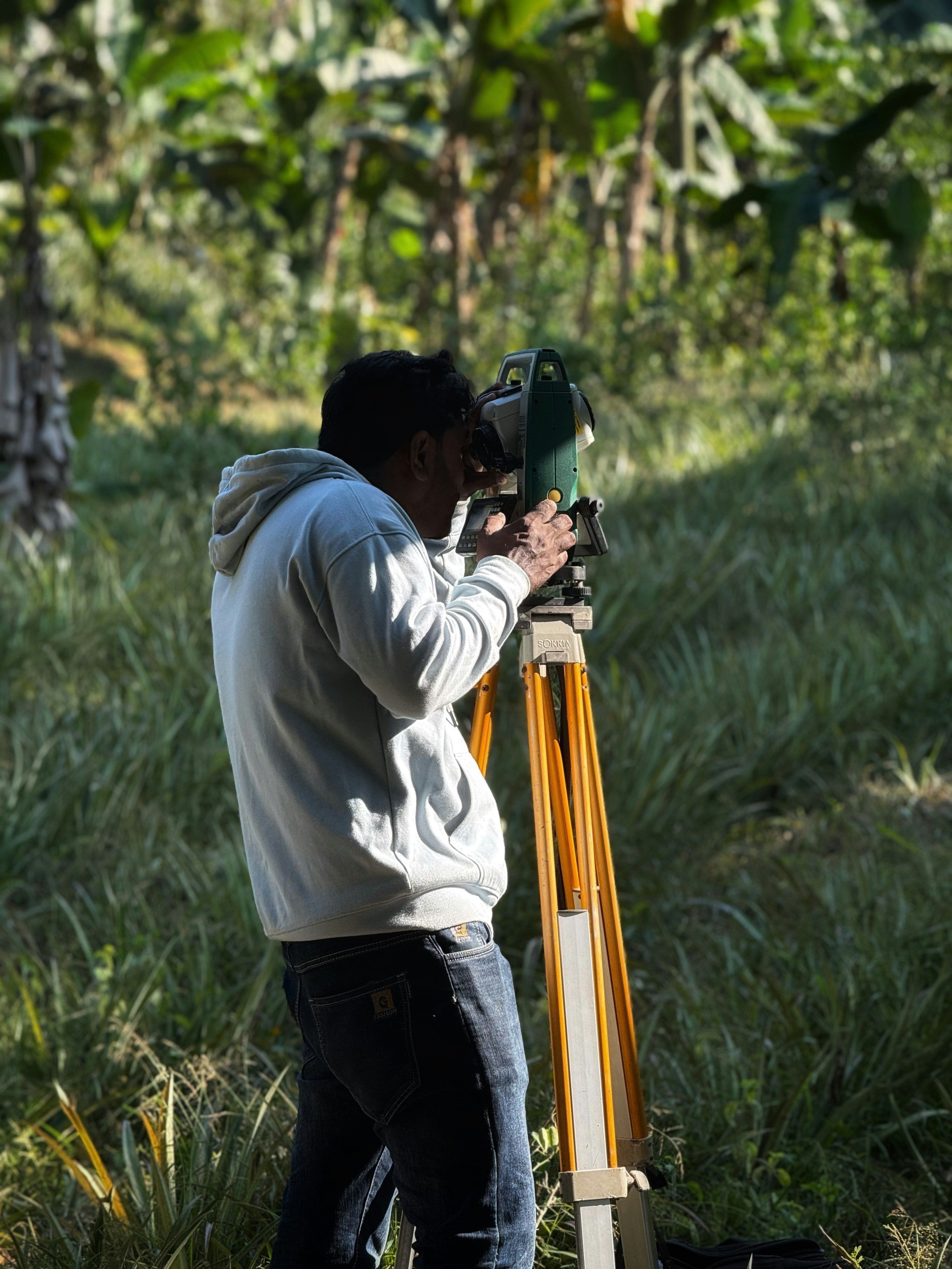 Man using a surveying instrument in a field.