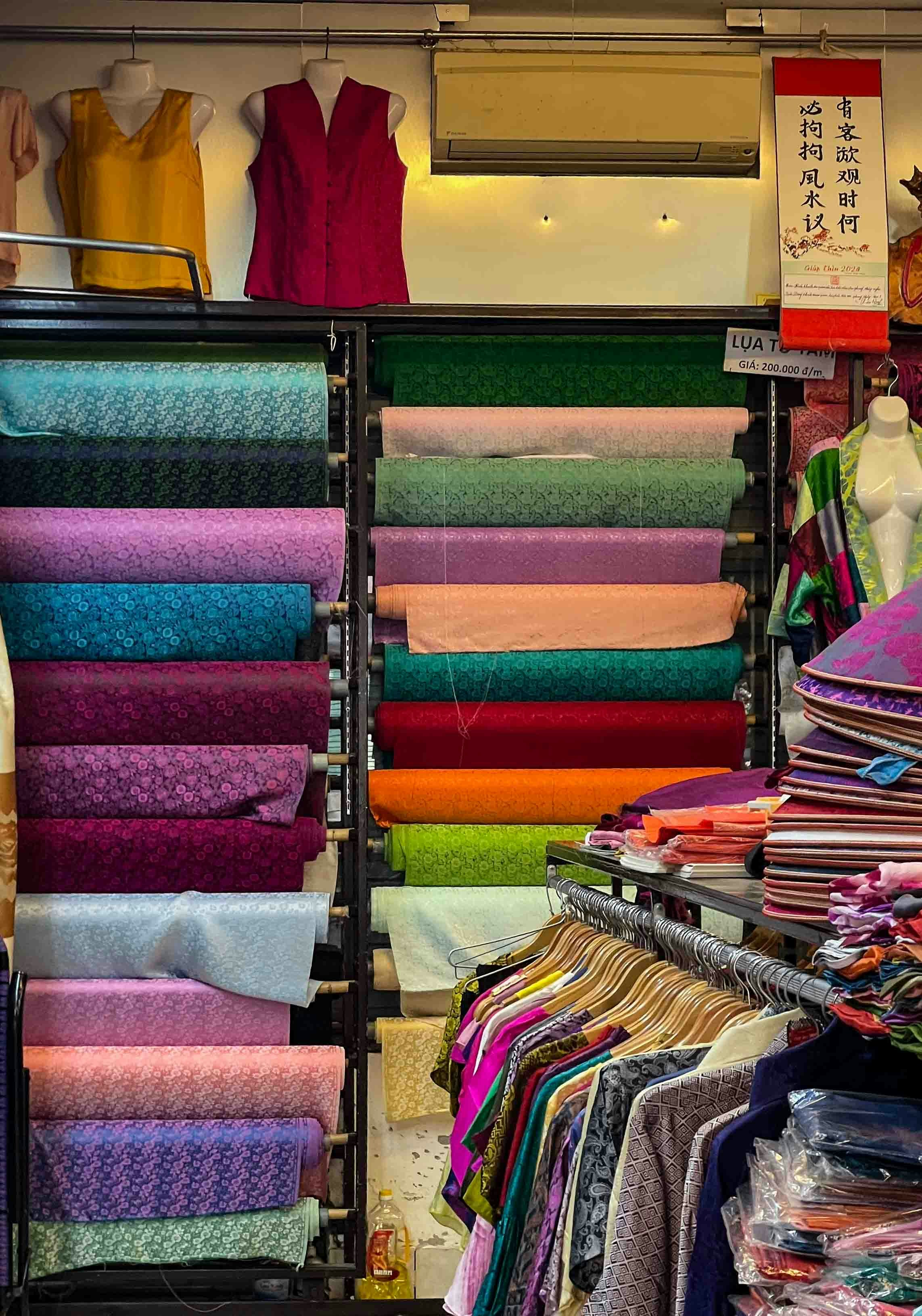 Colorful fabric rolls and clothing displayed in a shop.