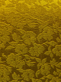 A textured golden fabric with a floral pattern.