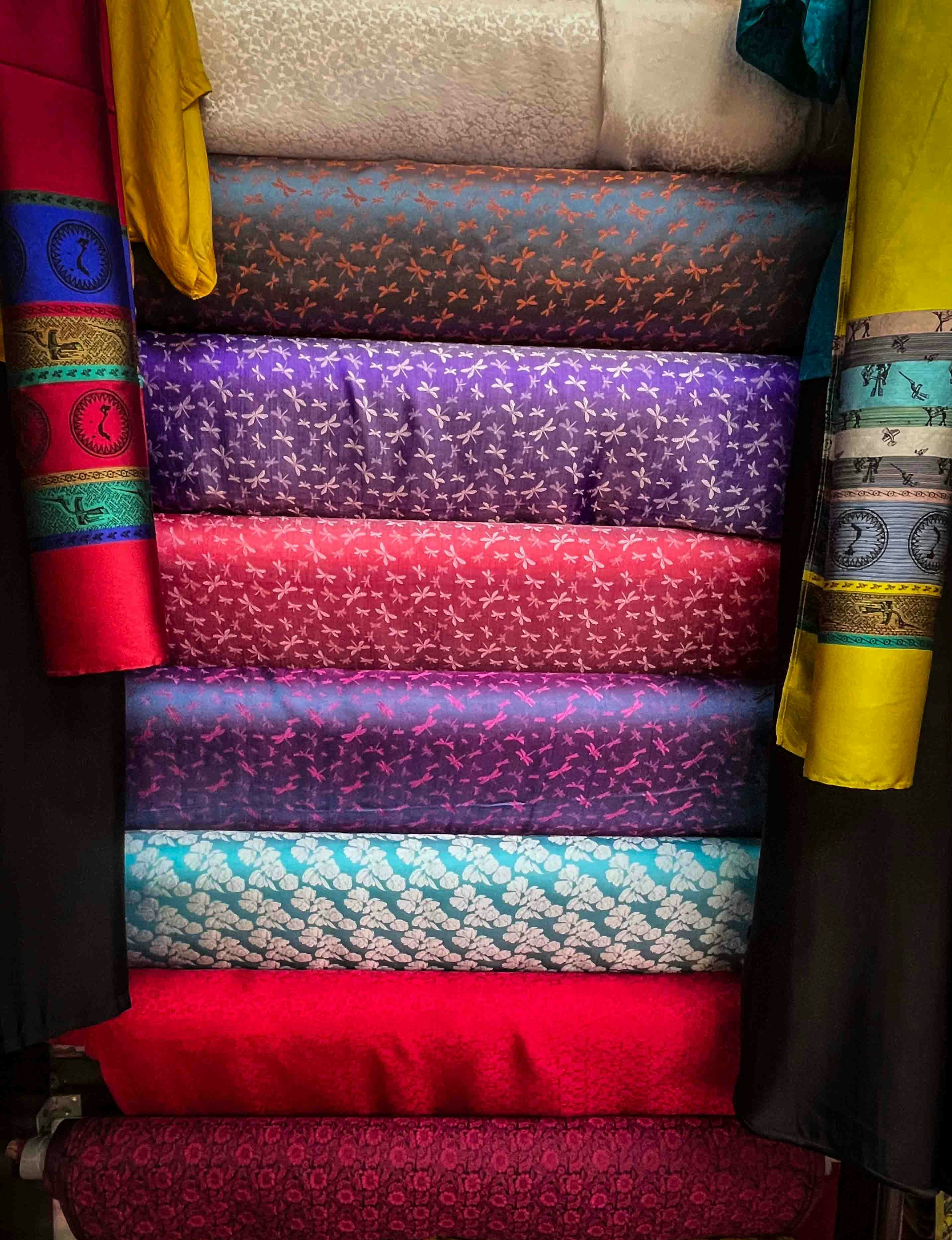 Stack of colorful patterned fabrics in a market