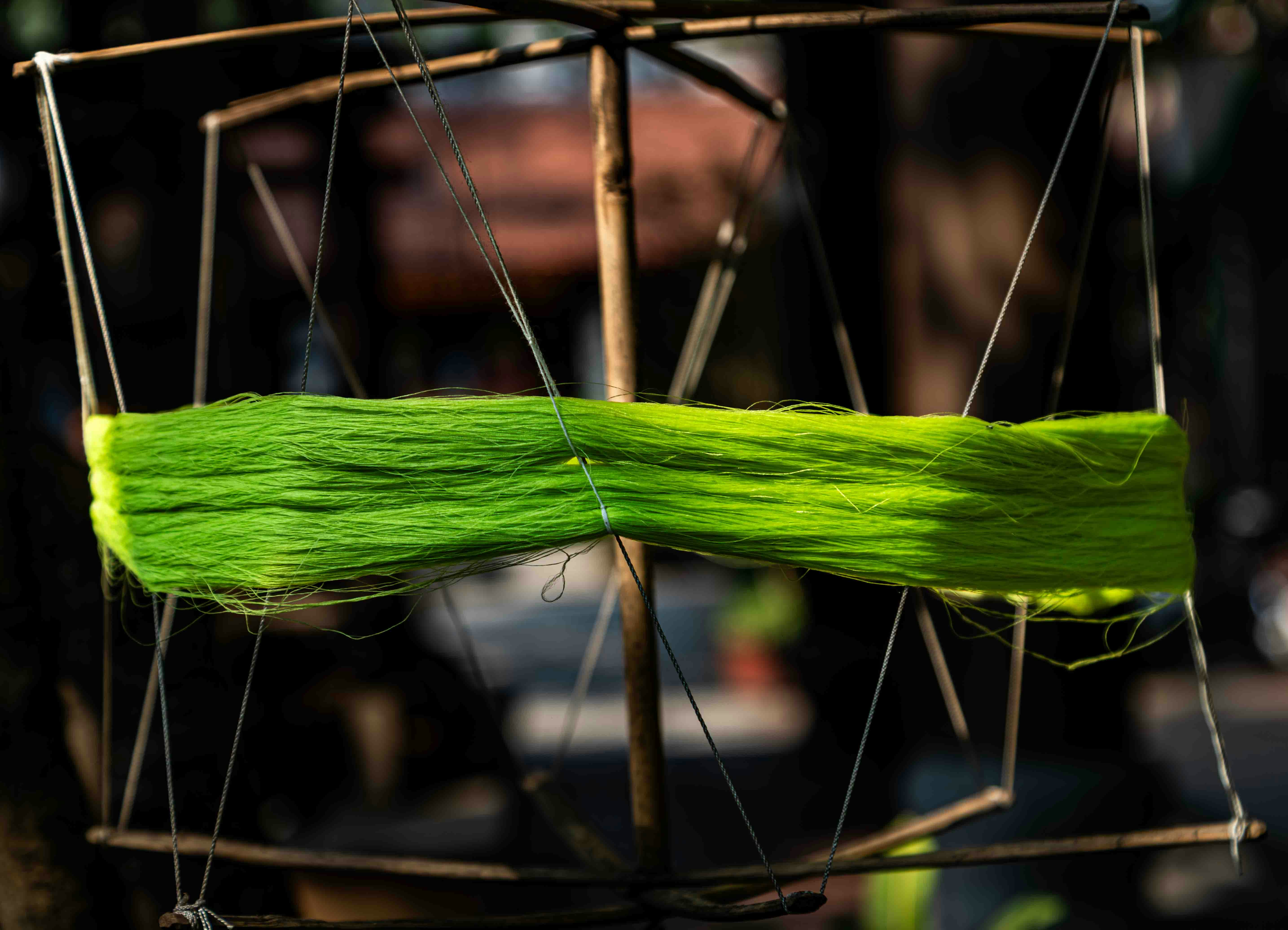 A spool of bright green thread on a wooden frame.