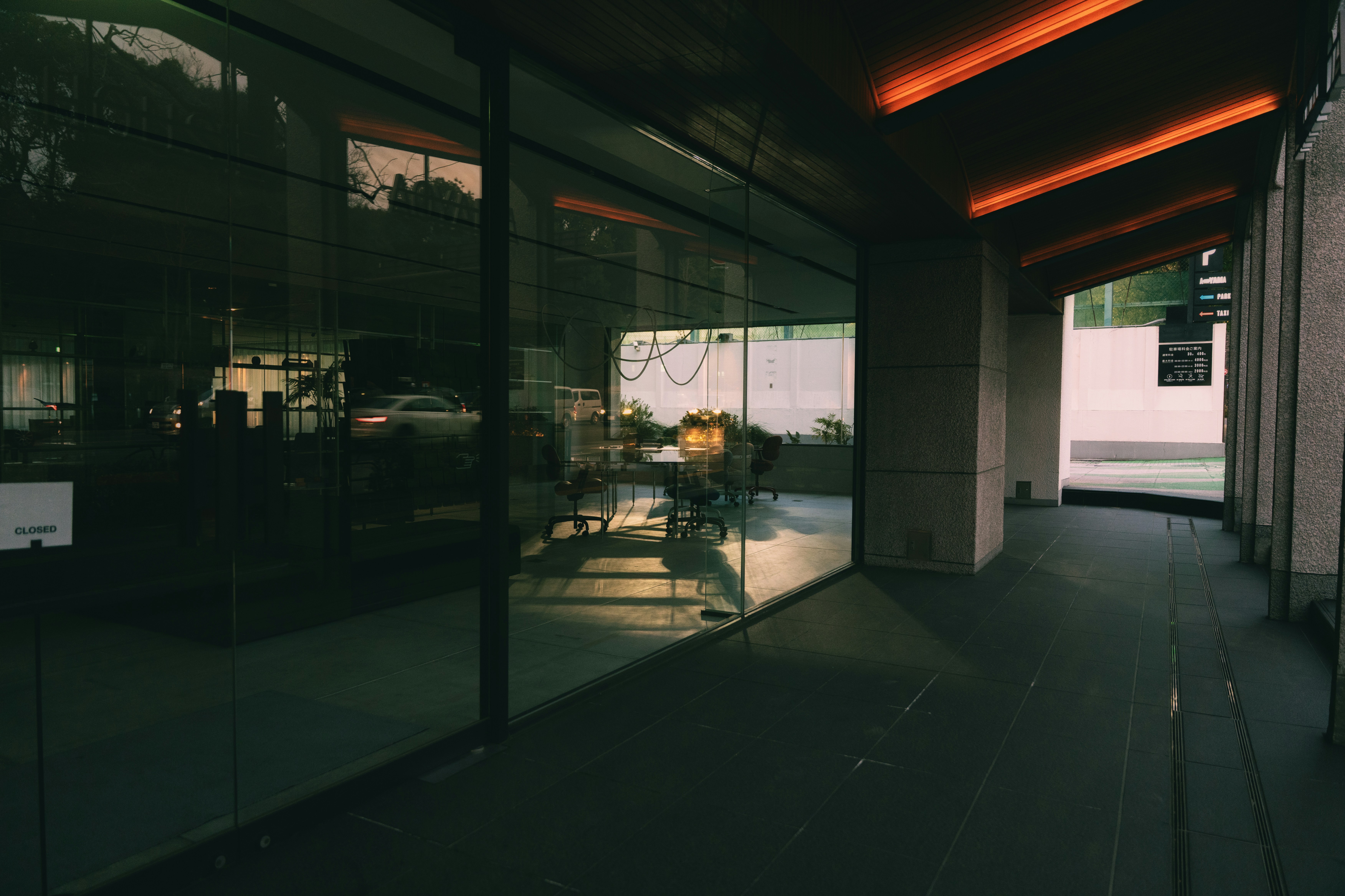 Modern building exterior with large glass windows and orange lights.
