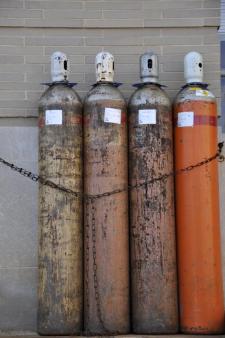 Four tall gas cylinders chained together outdoors