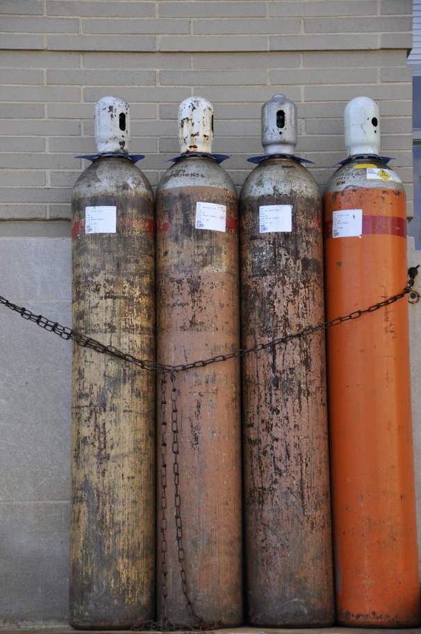Four tall gas cylinders chained together outdoors