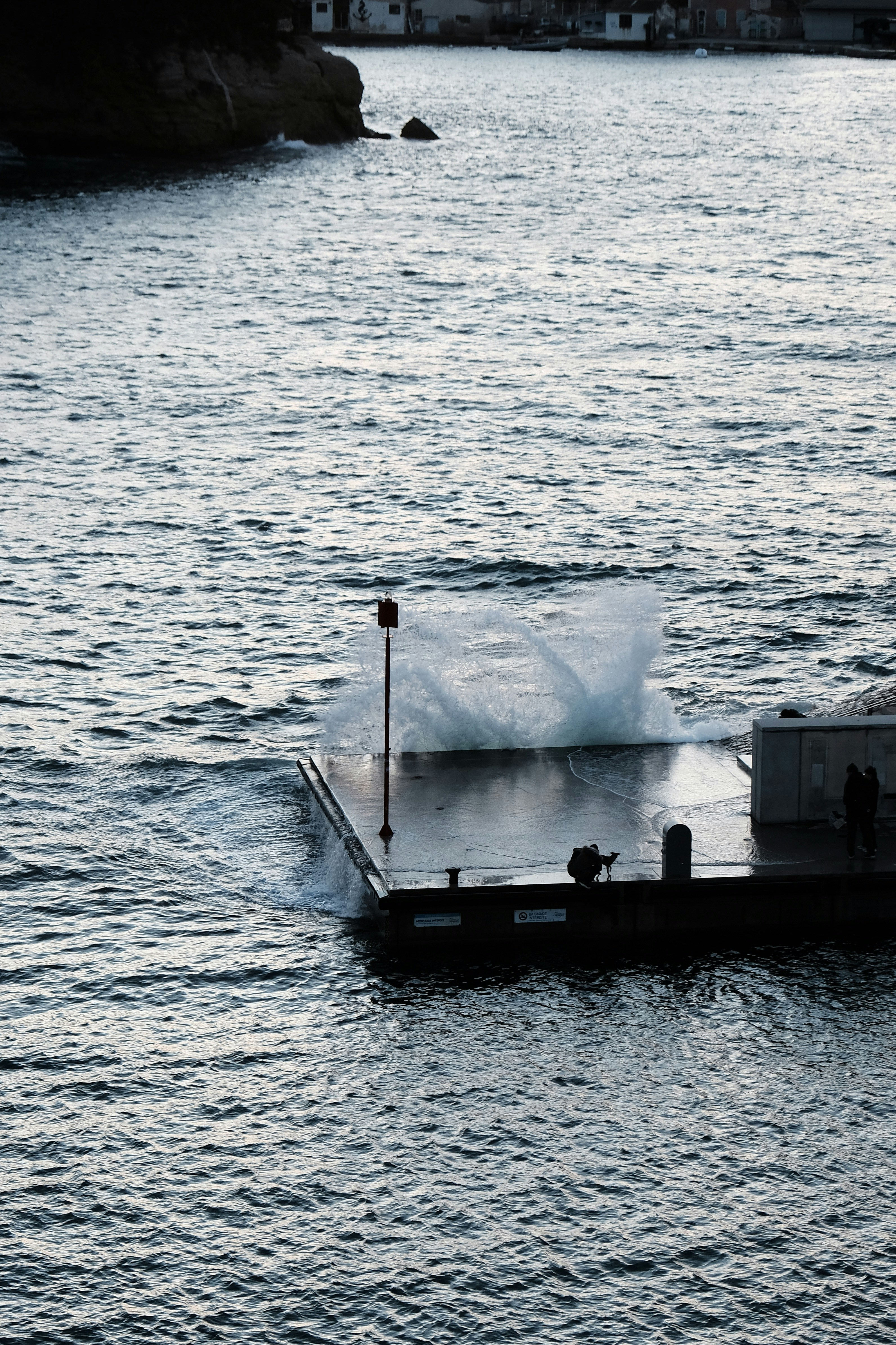 Ondas quebrando em um píer com duas pessoas