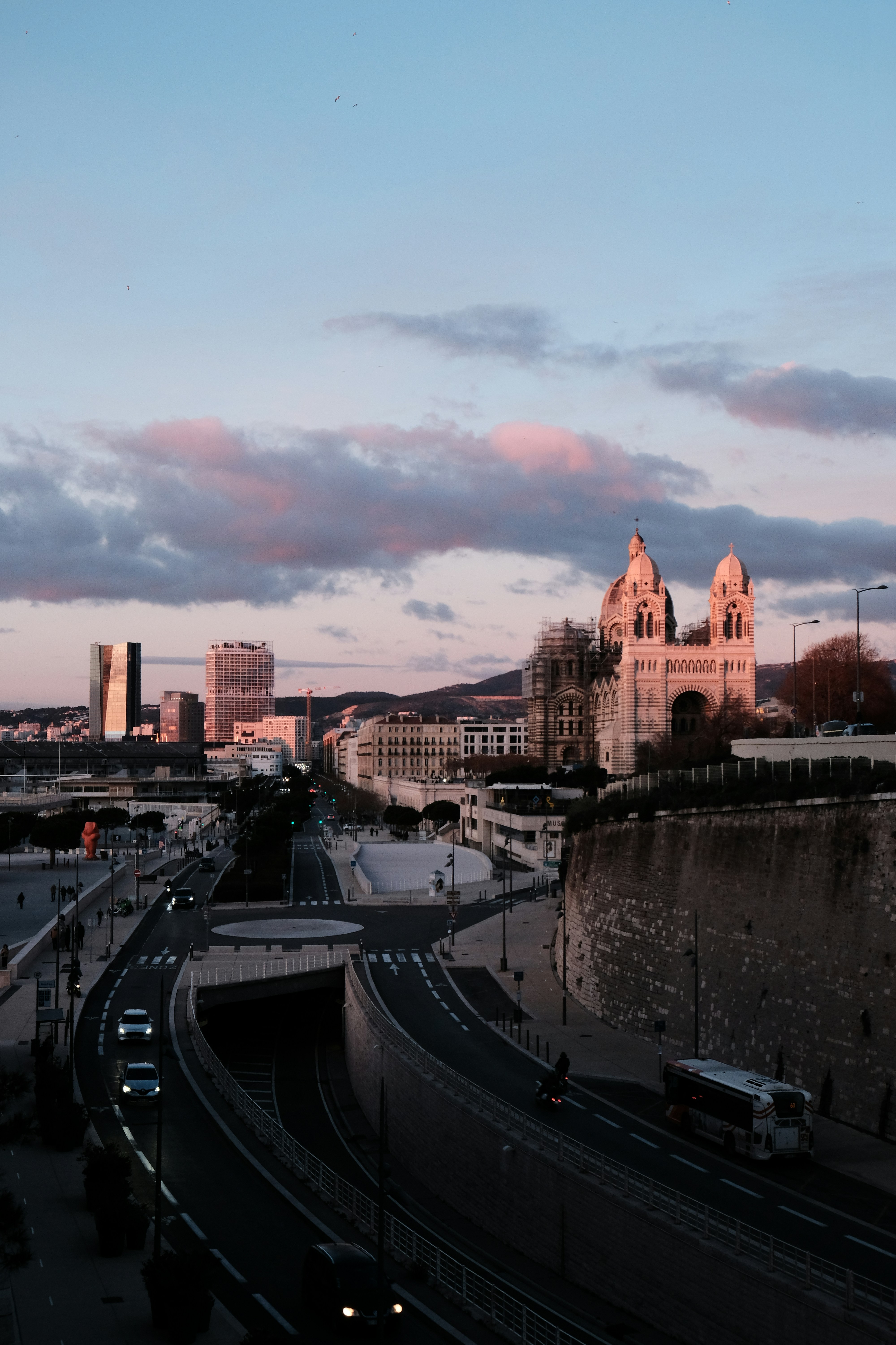 Paisagem urbana com basílica e prédios modernos ao entardecer.