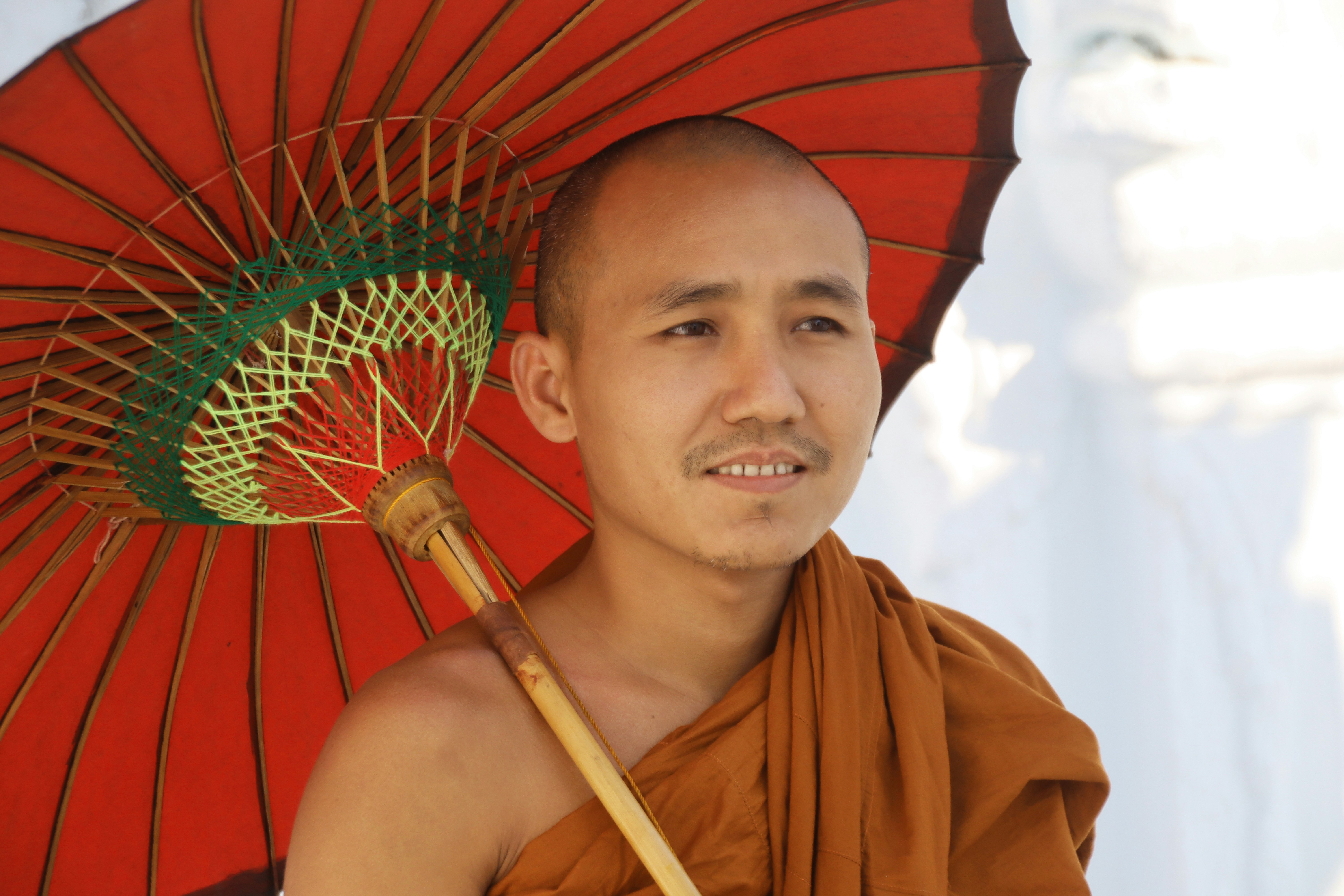 Monk holding a red umbrella in sunlight