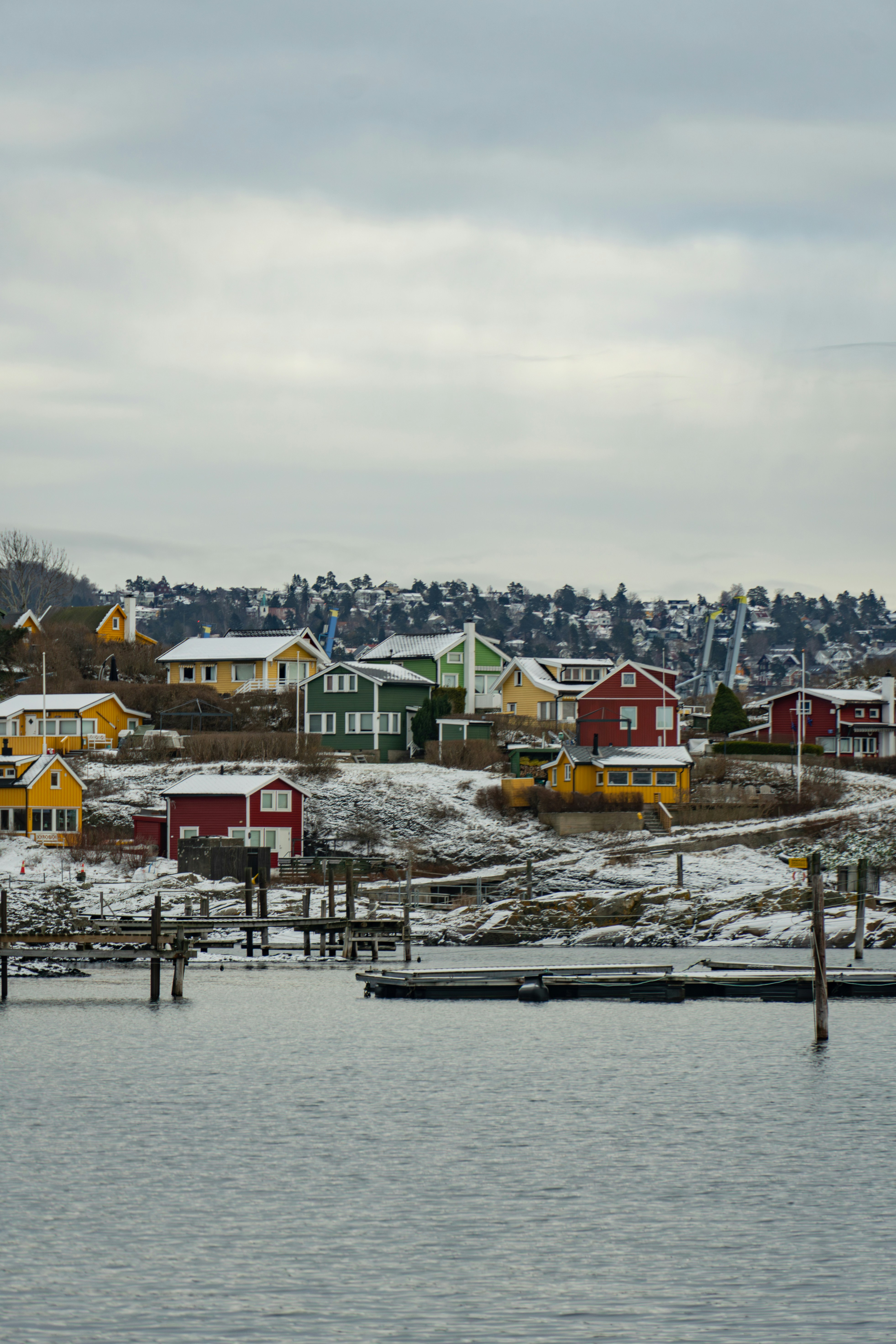 Colorful houses on a snowy hillside overlooking water.