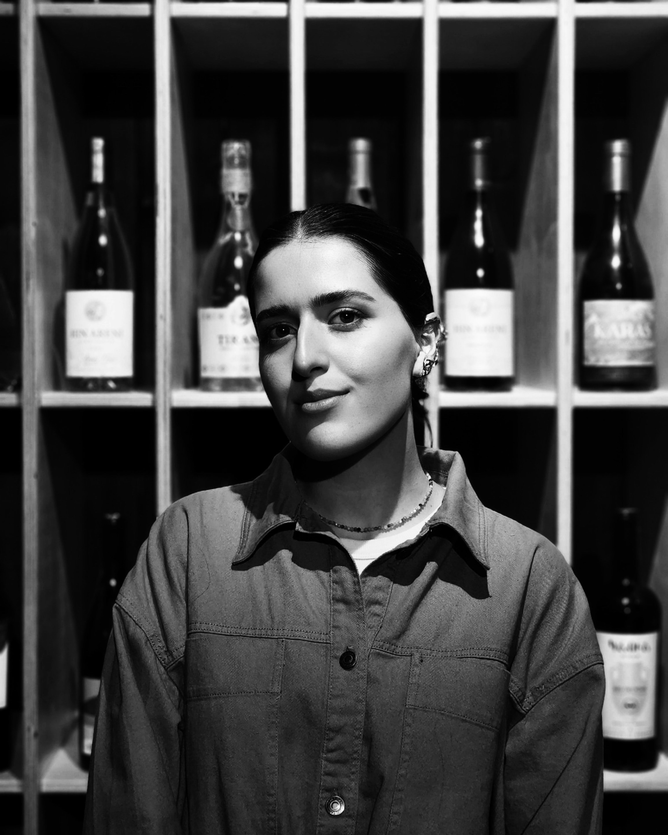 Donna in piedi davanti a bottiglie di vino sugli scaffali