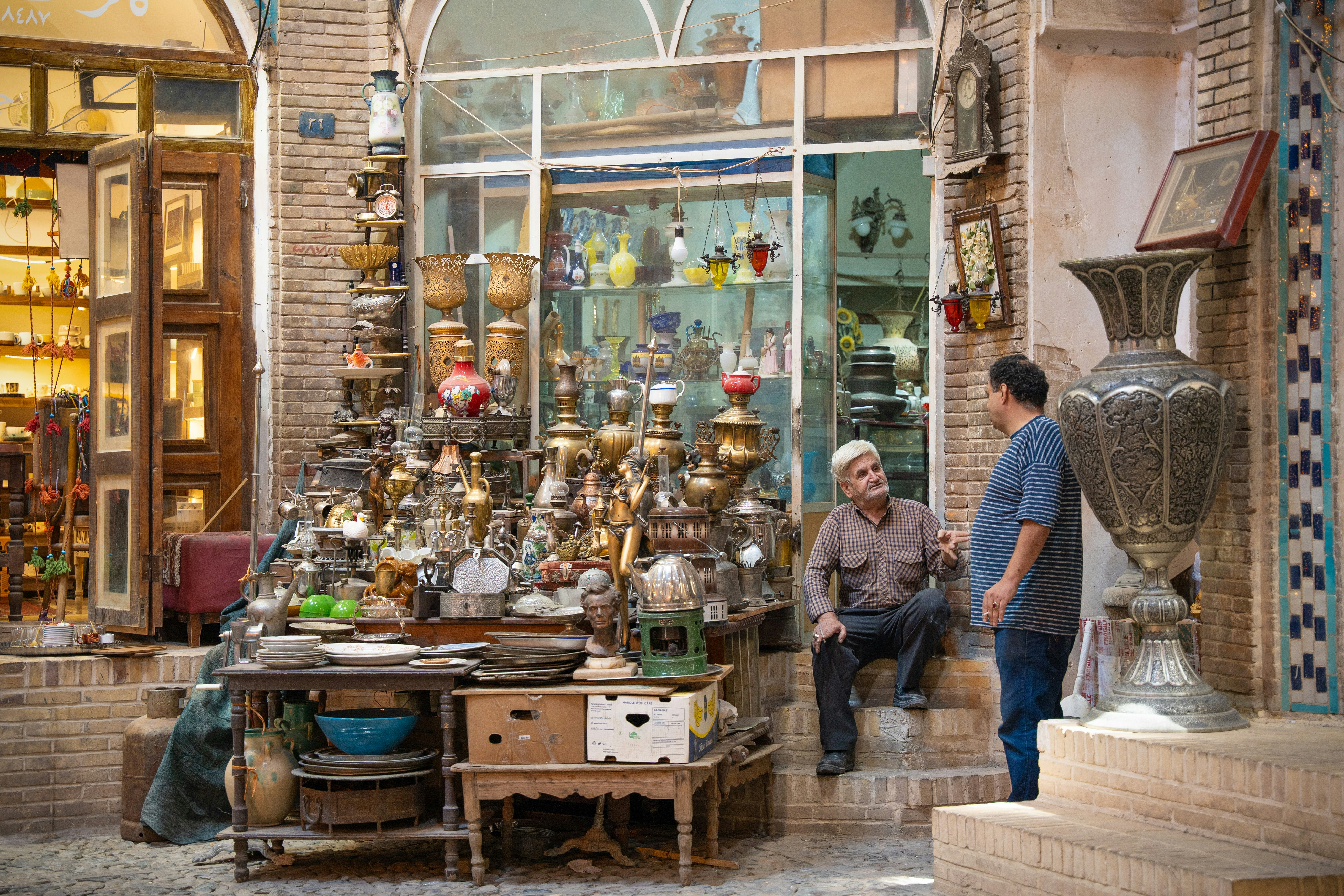 Two men talking in front of an antique shop.