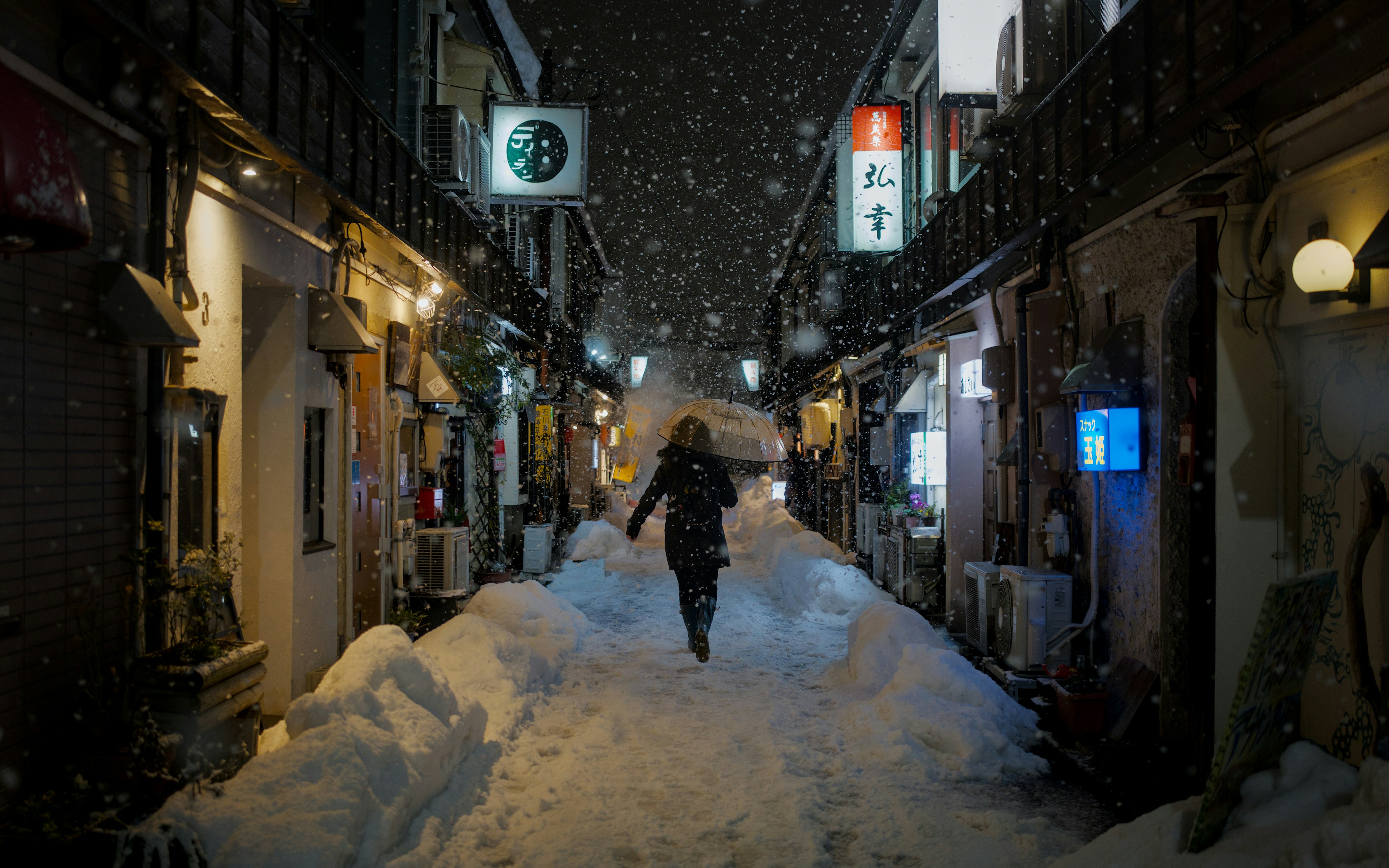 A person runs down a snowy alley at night.