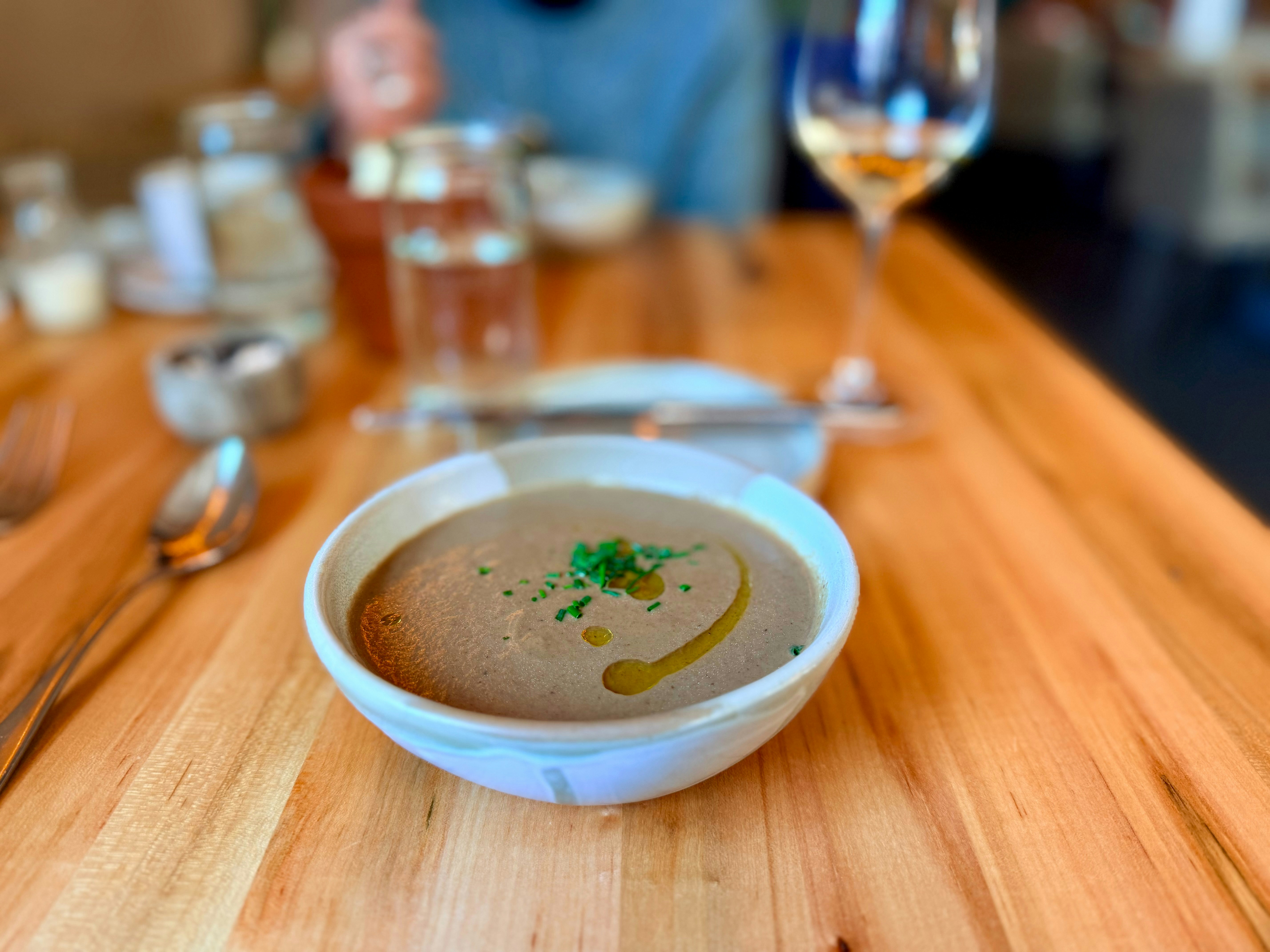 Bowl of creamy mushroom soup with garnish on table