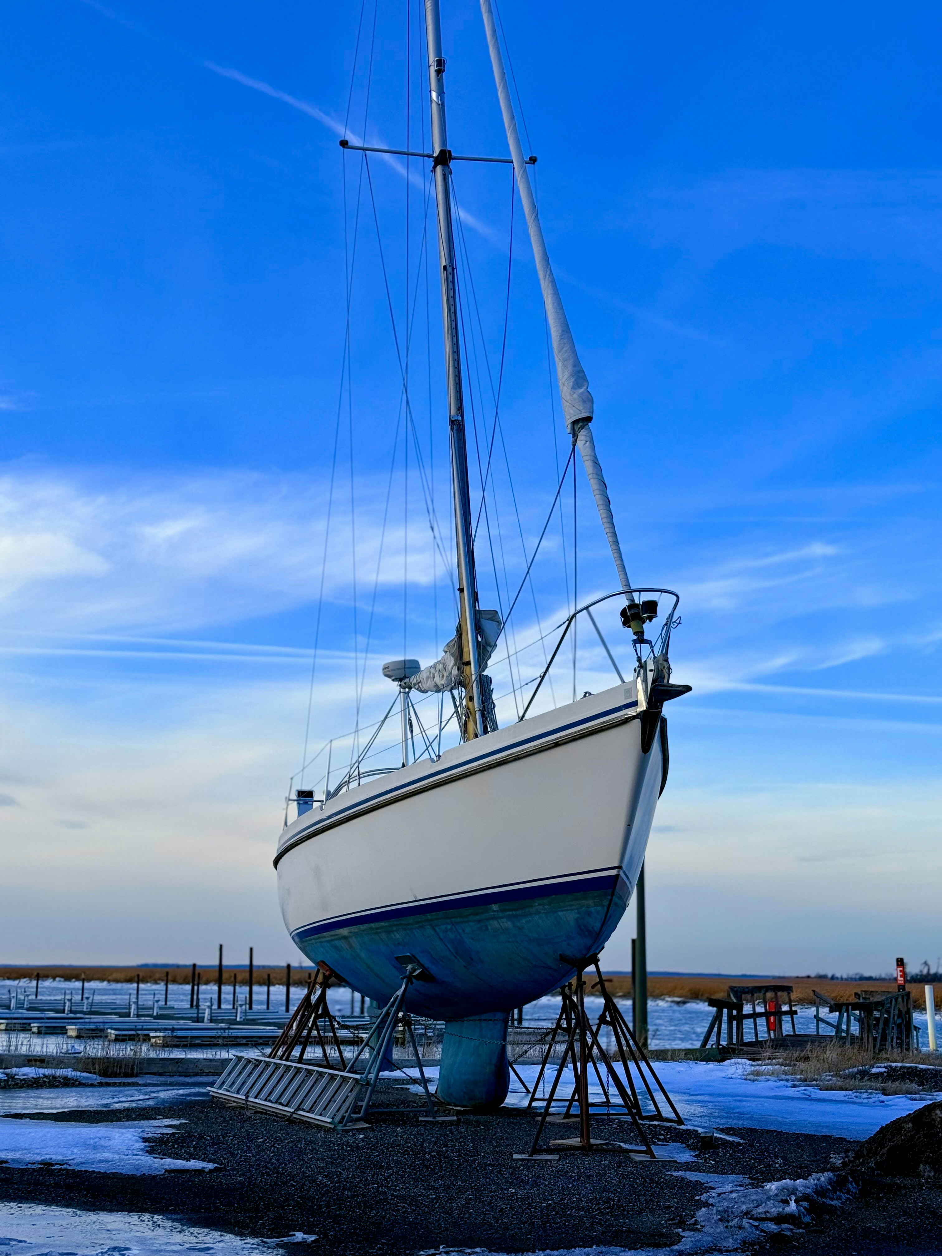 A white sailboat rests on stands under a blue sky.