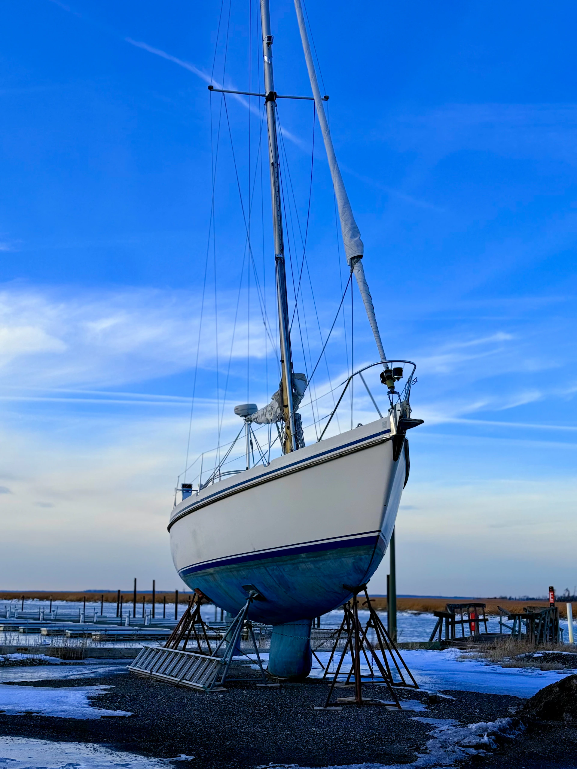 A white sailboat rests on stands under a blue sky.