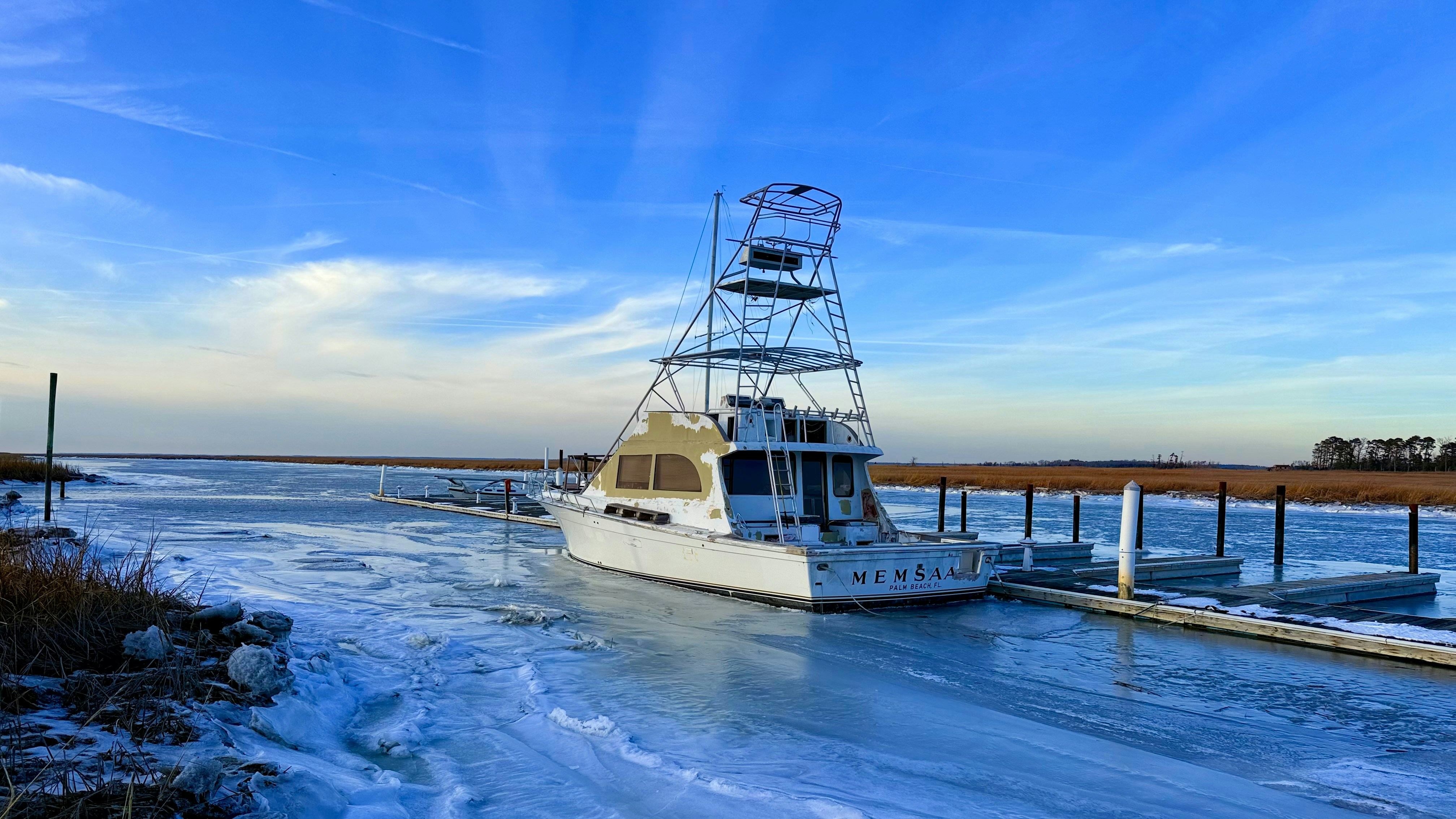 A white boat docked in a frozen waterway.