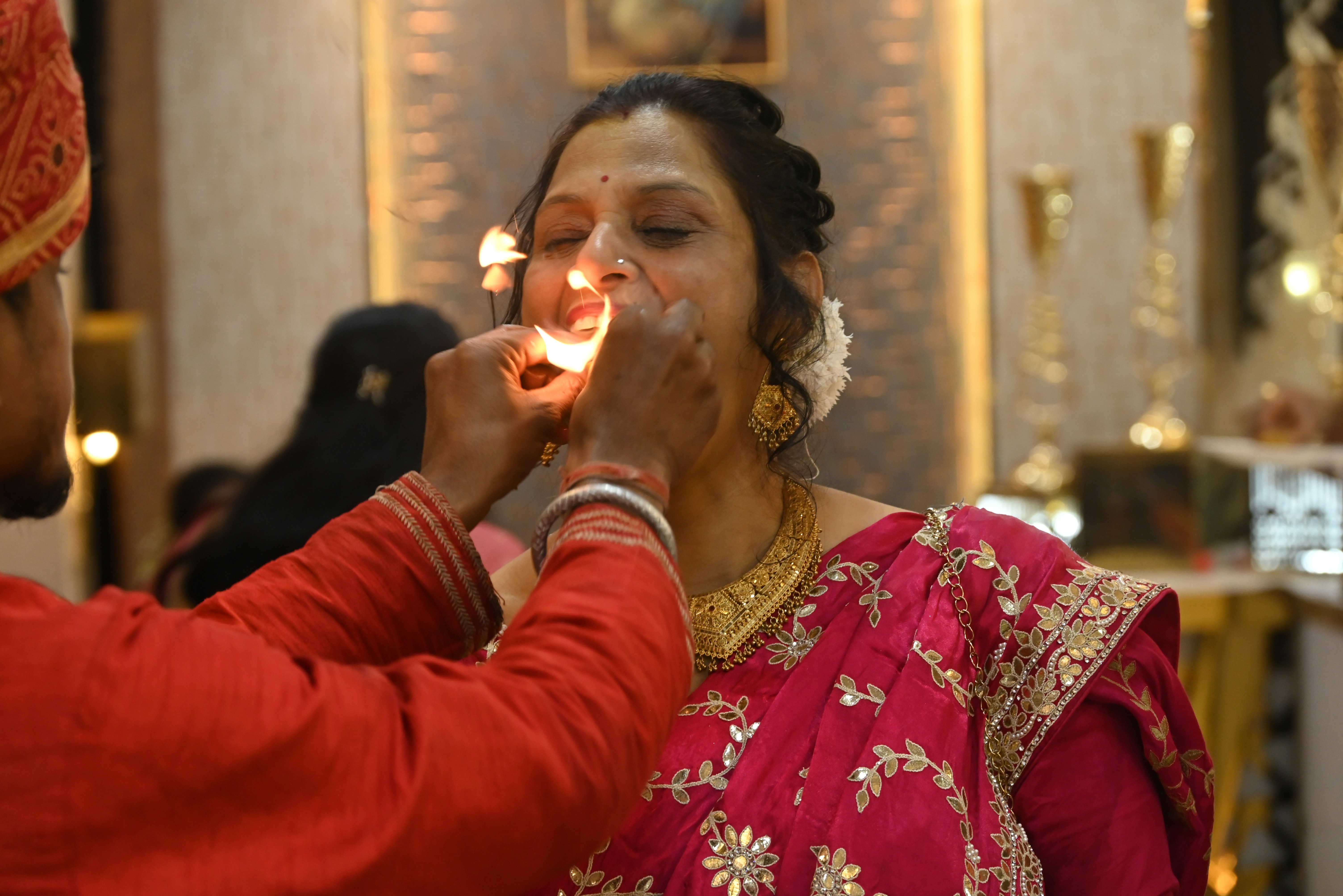 A woman's face with a lit candle near her mouth.