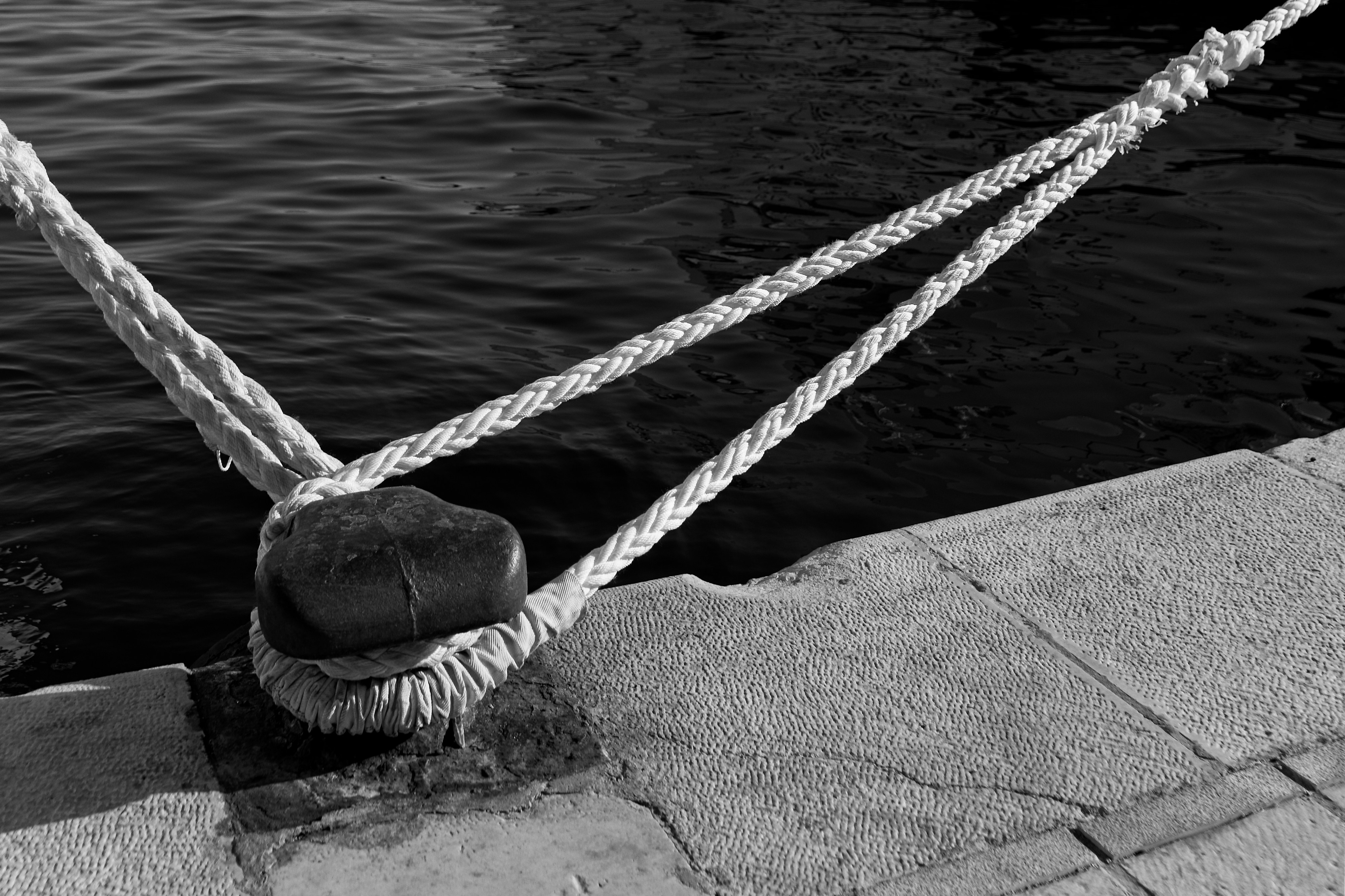 Cuerda gruesa sujeta a un bolardo junto al agua.