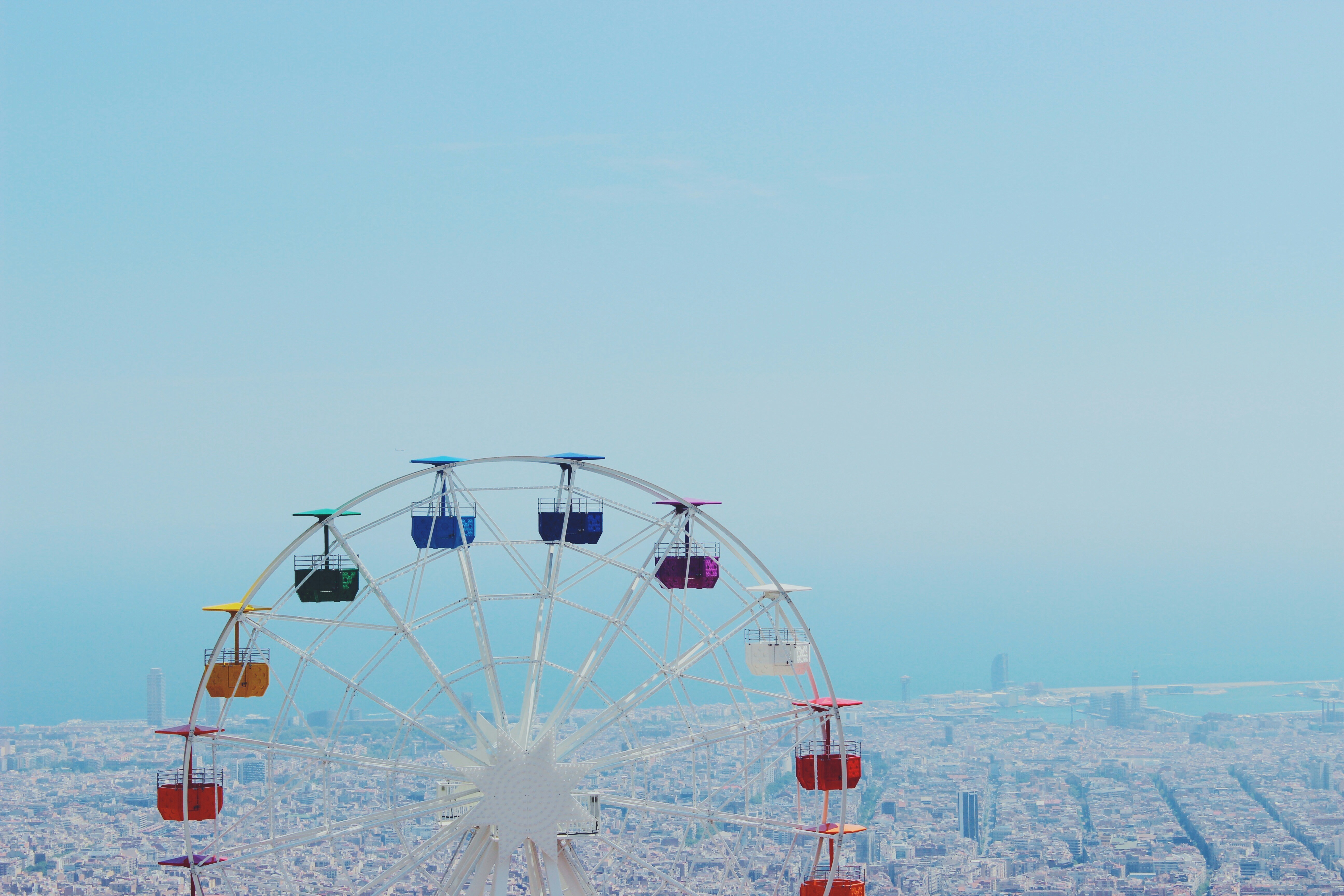 Ferris wheel with colorful cabins over a city