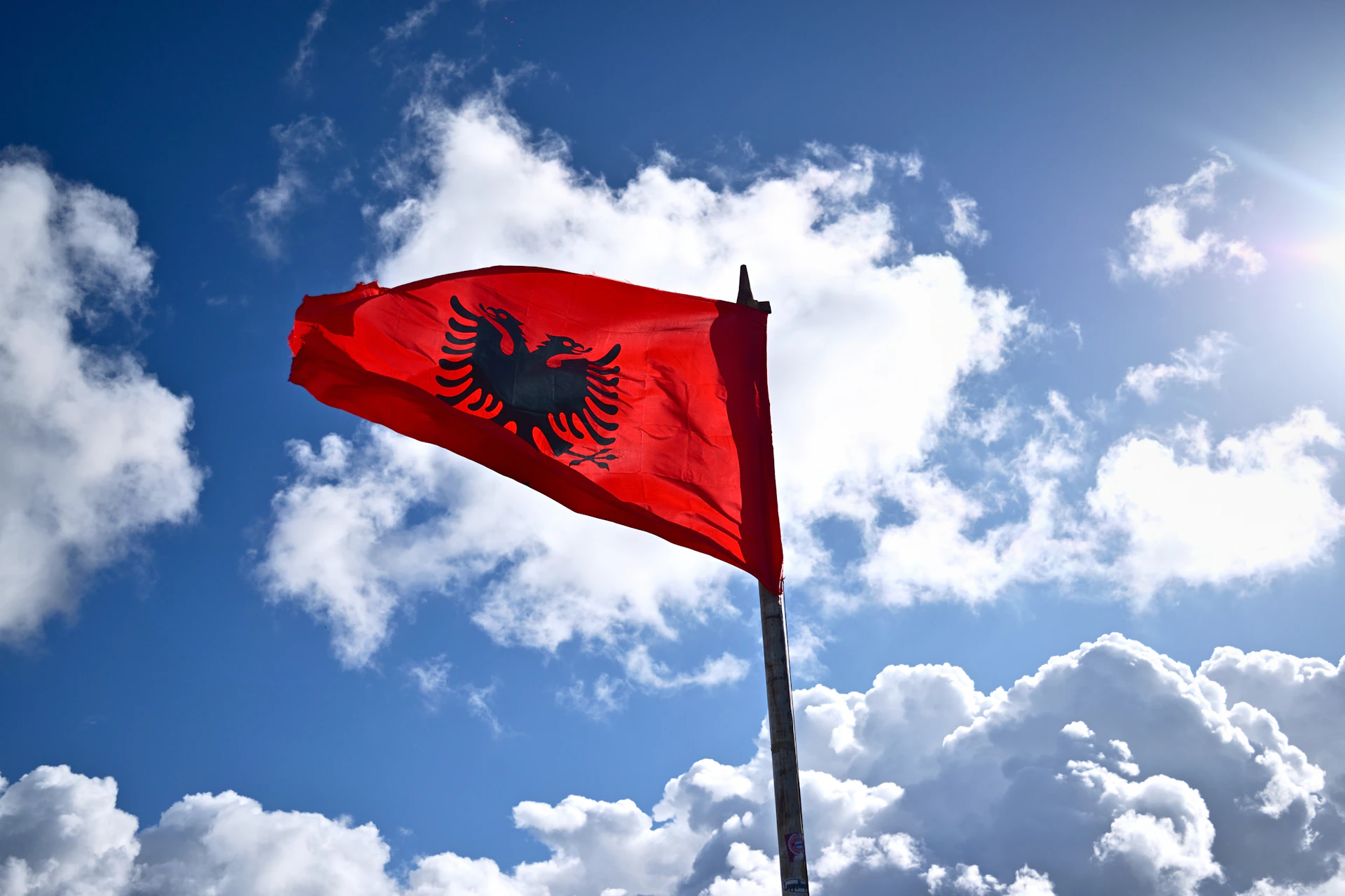 Albanian flag waving against a cloudy blue sky