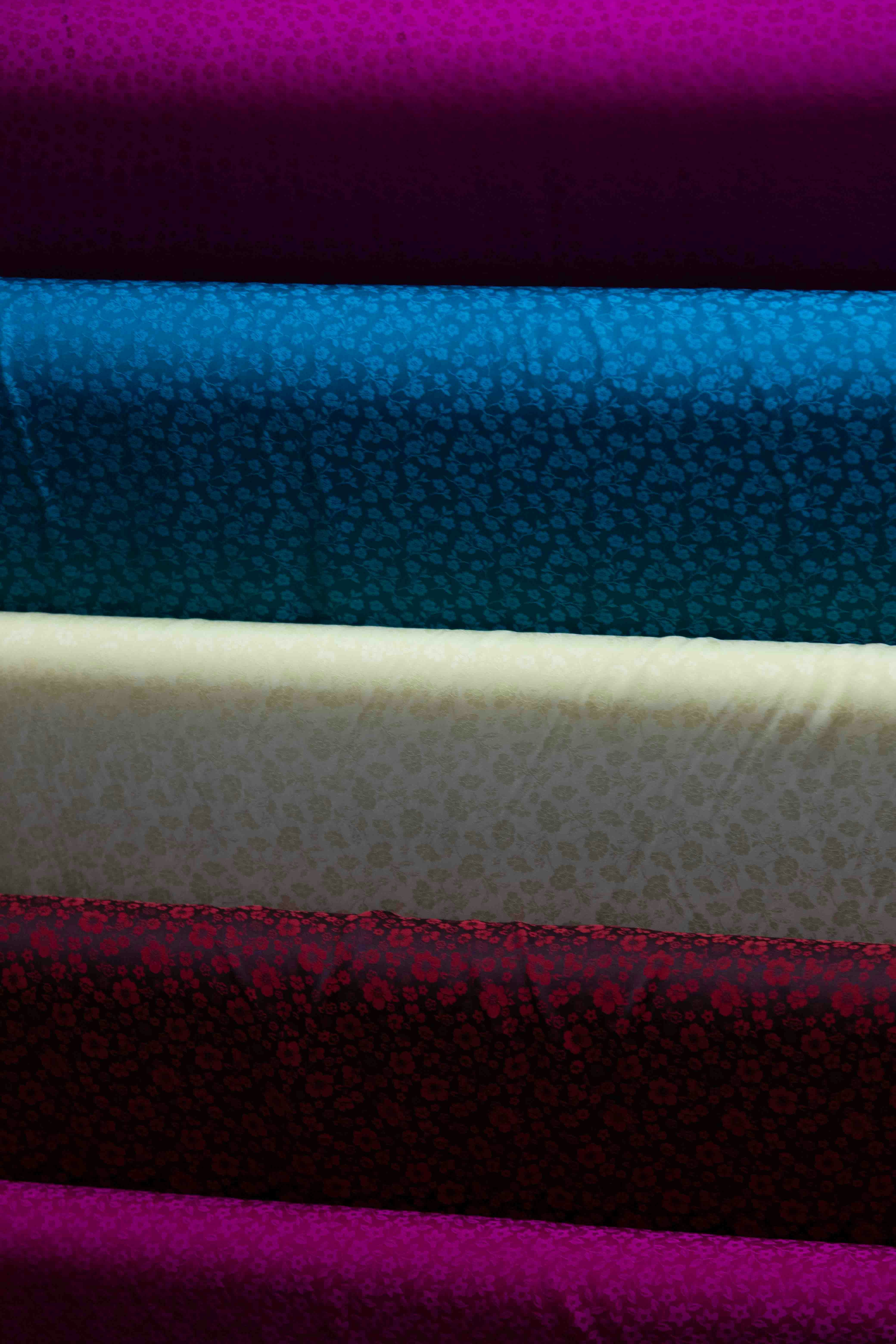 Stacked fabric rolls in various colors and patterns