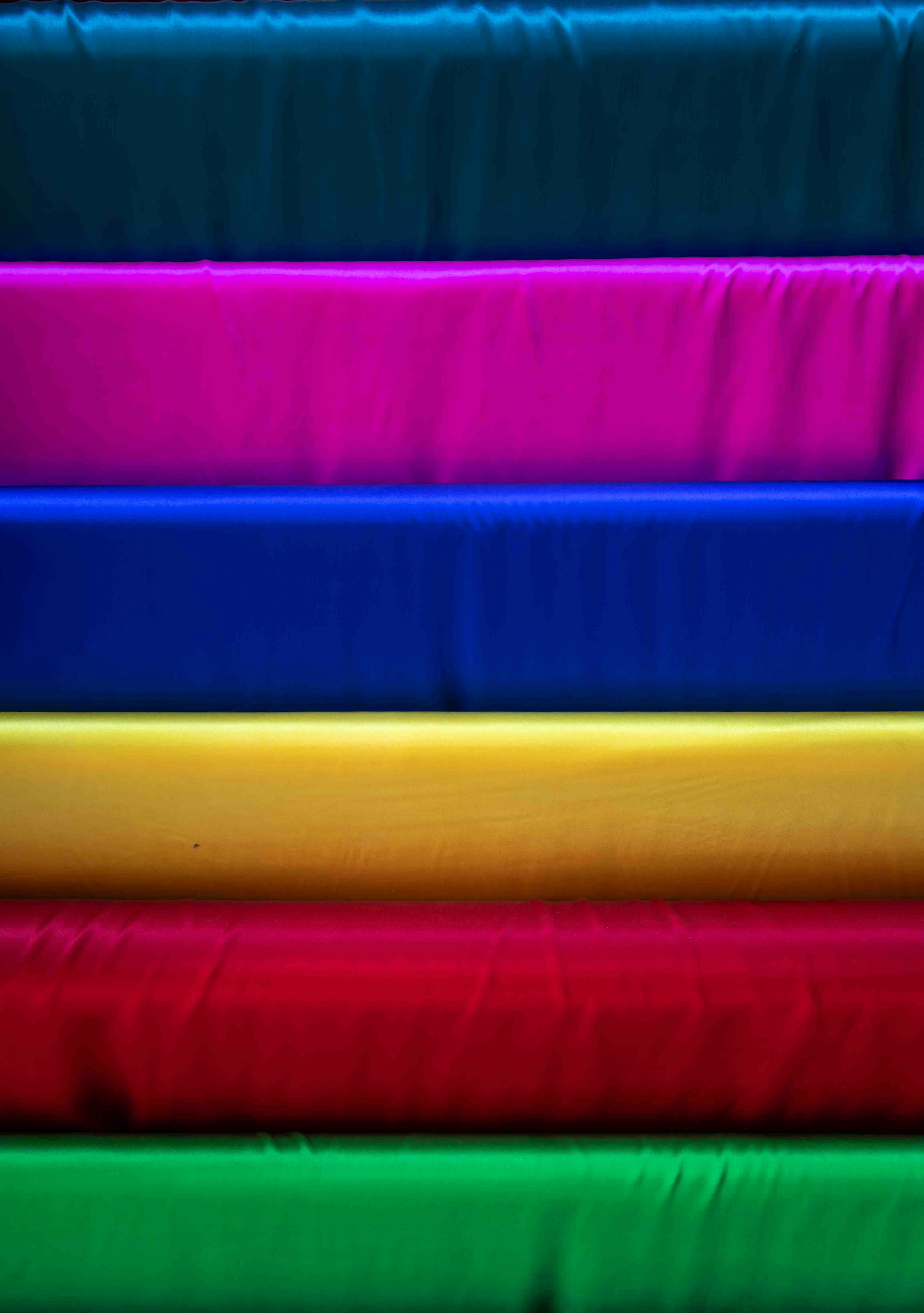 Stacked rolls of colorful fabric in vibrant hues.