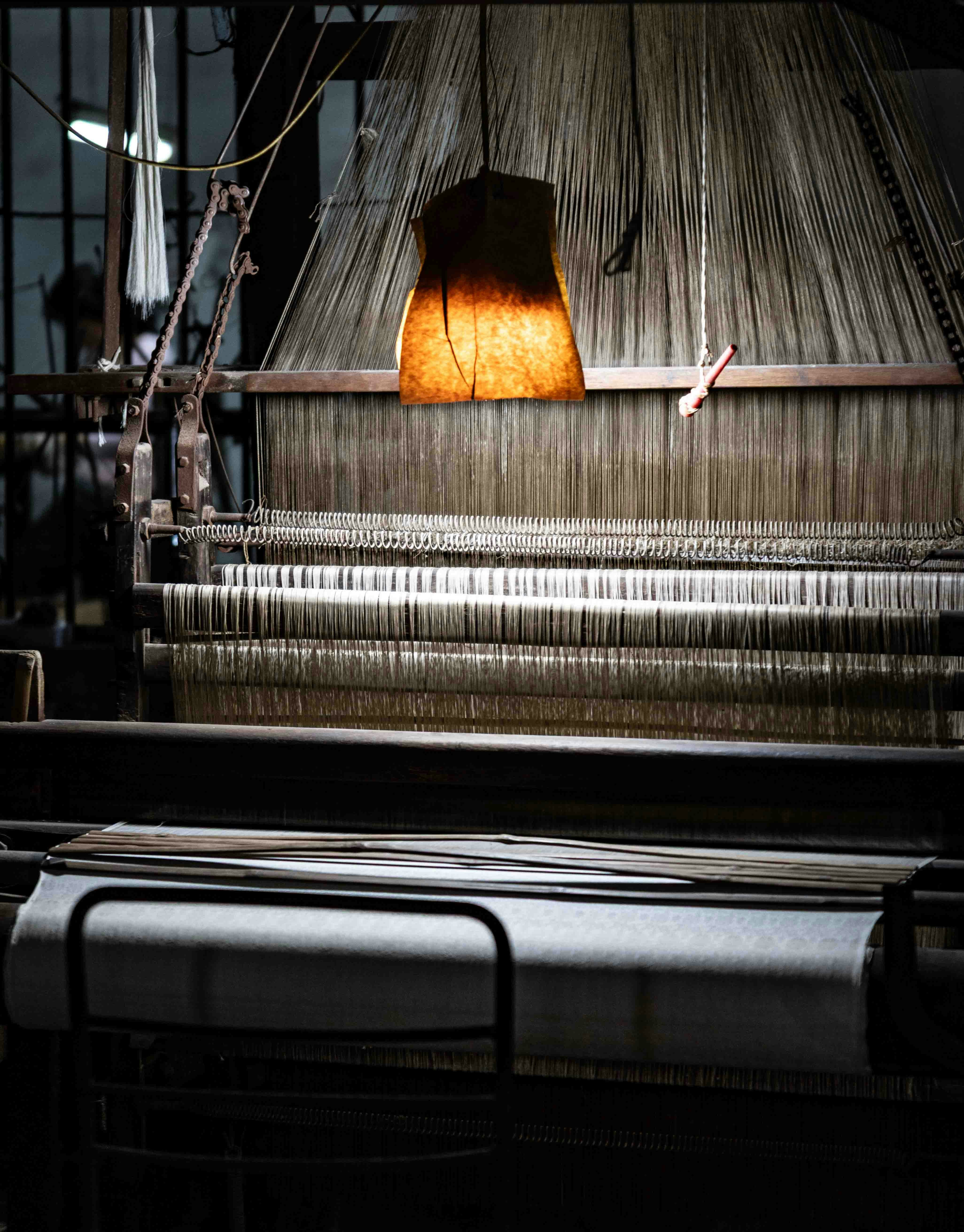 Old weaving loom with warm light illuminating threads.