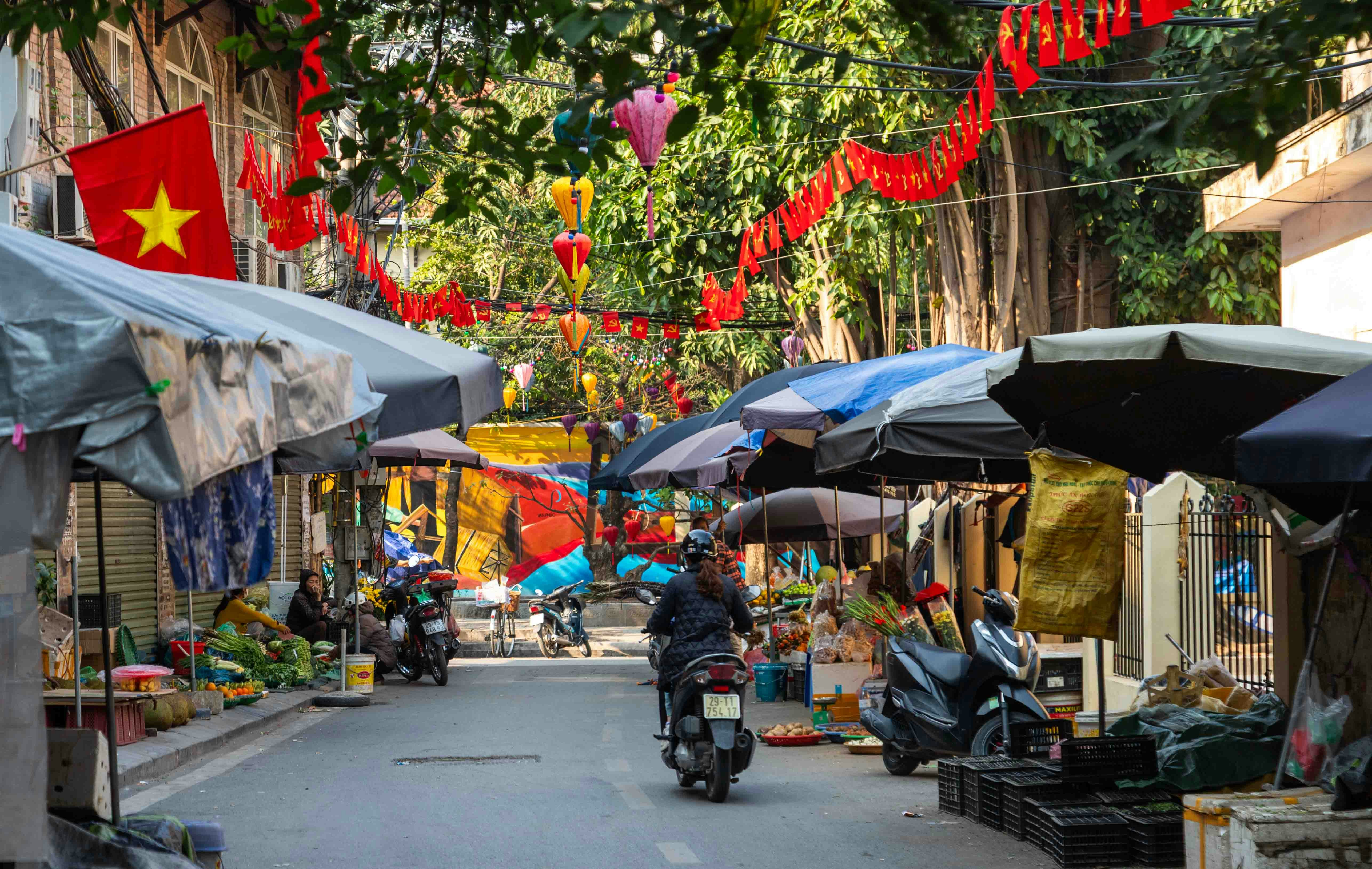 Street market with stalls and people on motorbikes