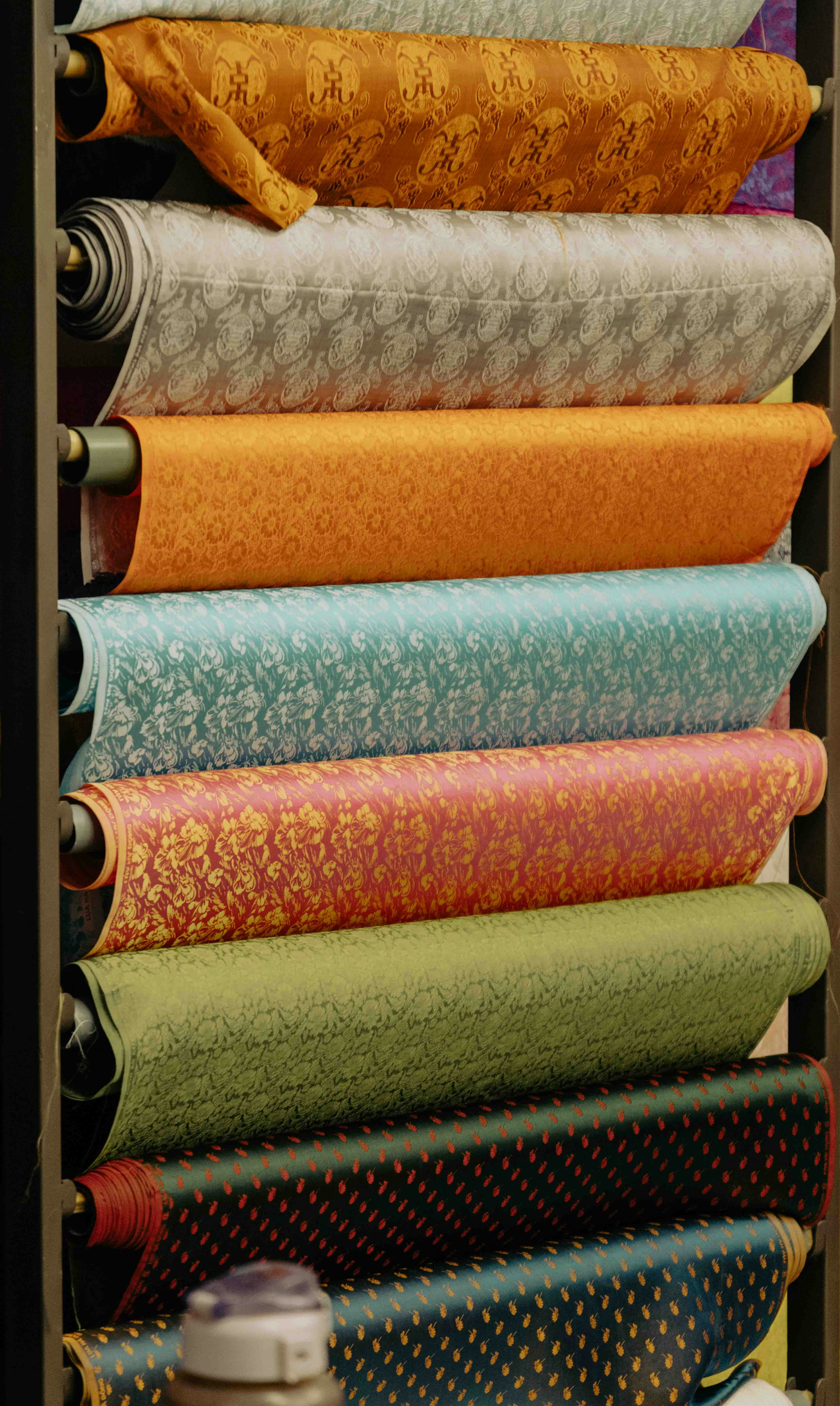 Rolls of patterned fabric stacked on shelves